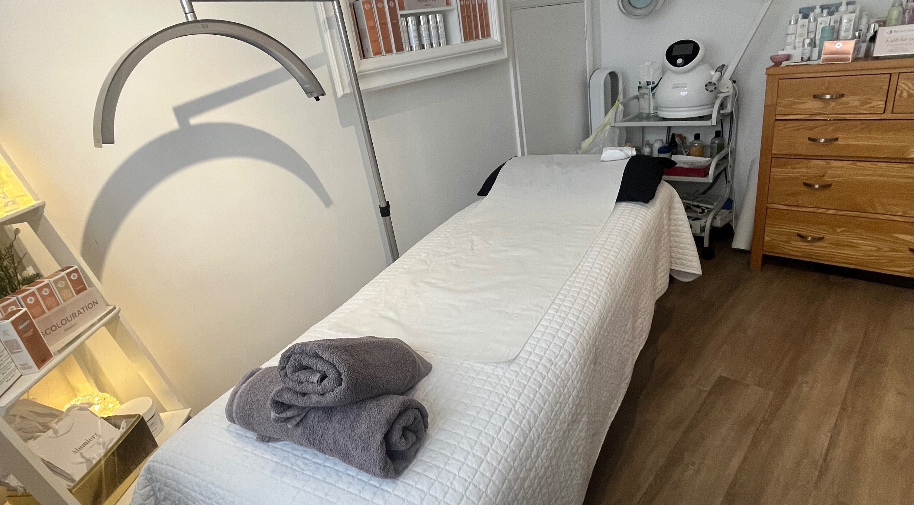 Tranquil treatment room at The Peel Queen, Addlestone, England, GB, featuring a treatment bed with neatly folded towels.