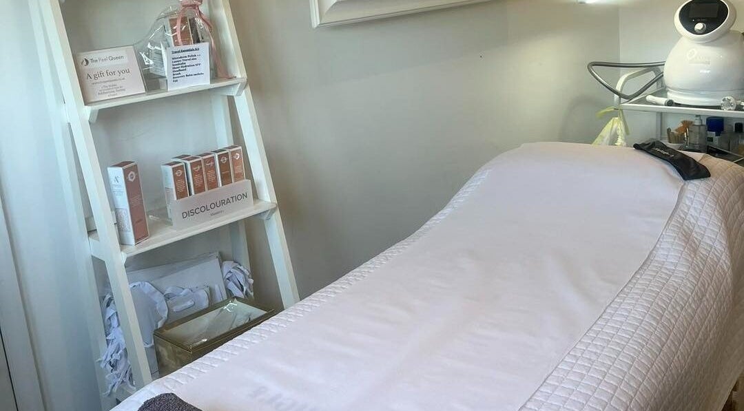 Treatment room at The Peel Queen, Addlestone, England, GB, featuring a cozy bed and skincare products on display.