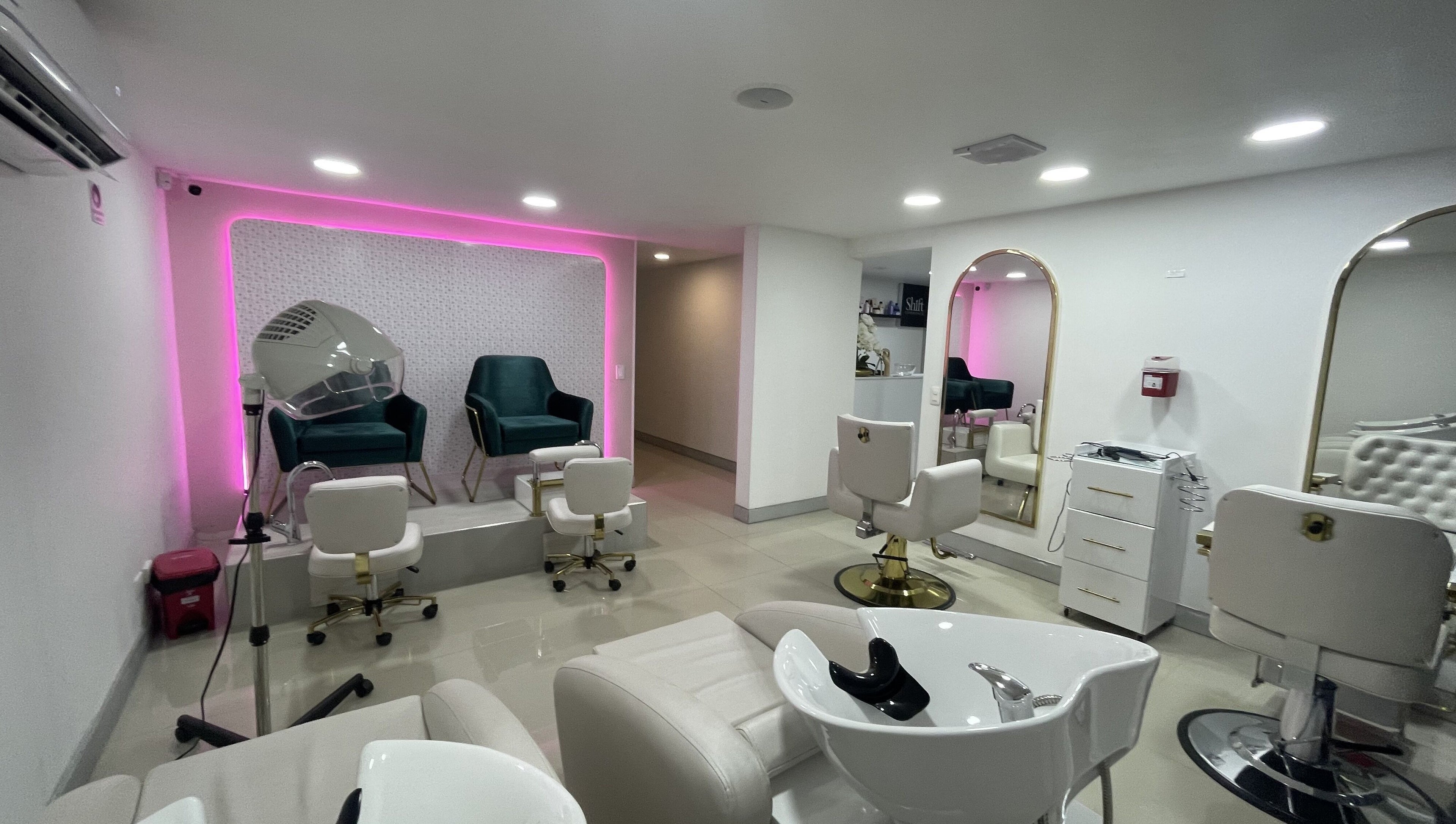 Zona elegante de salón en Shift Experience, Cali, Valle del Cauca, CO con asientos y espejos iluminados.
