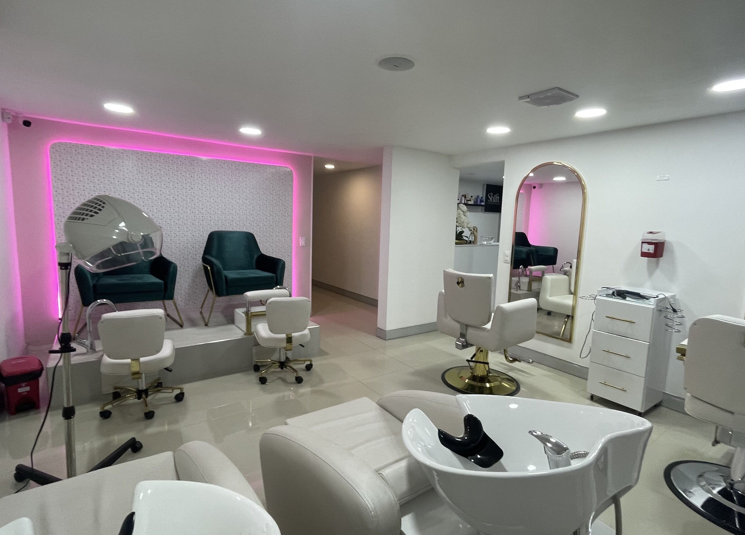 Zona elegante de salón en Shift Experience, Cali, Valle del Cauca, CO con asientos y espejos iluminados.