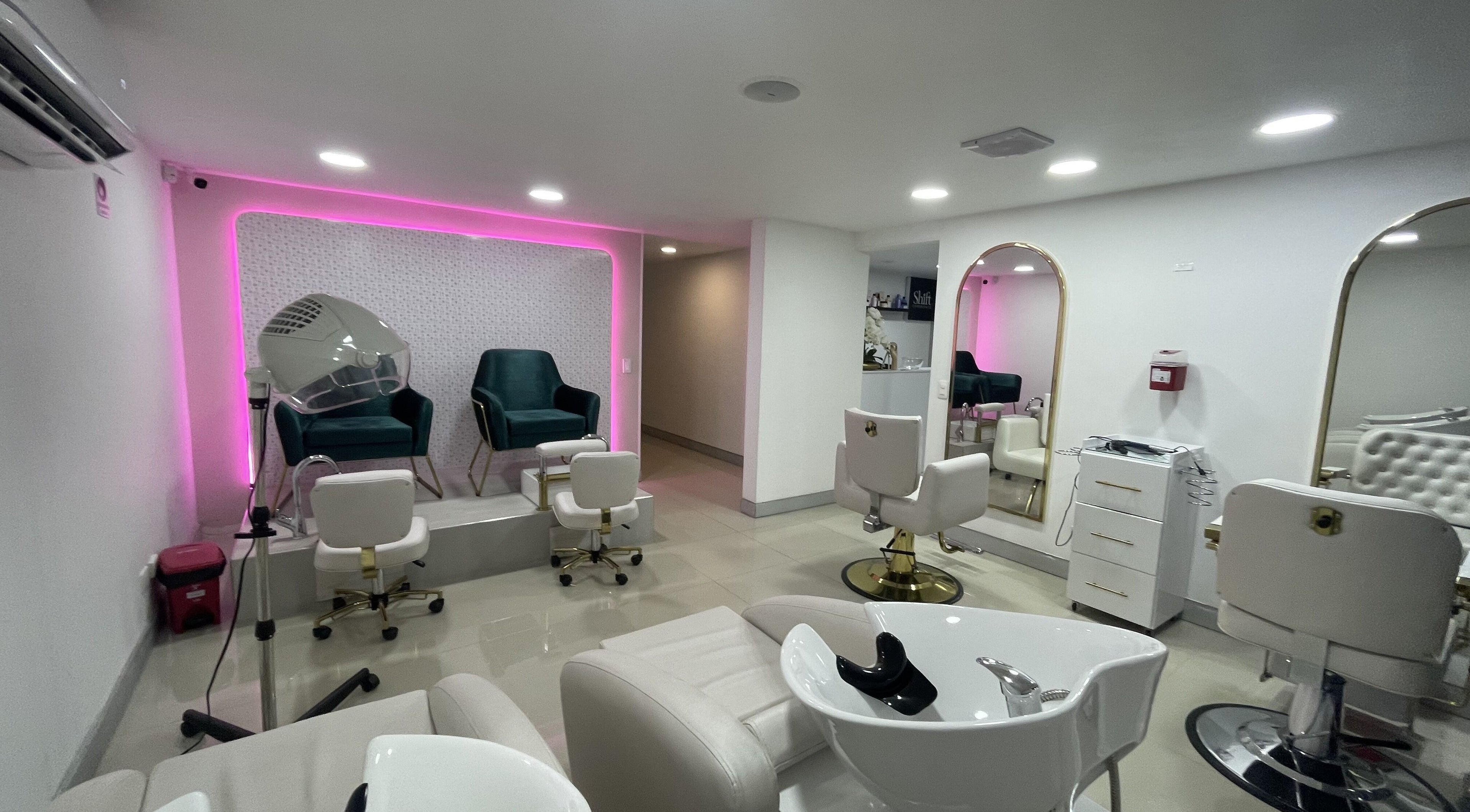 Zona elegante de salón en Shift Experience, Cali, Valle del Cauca, CO con asientos y espejos iluminados.