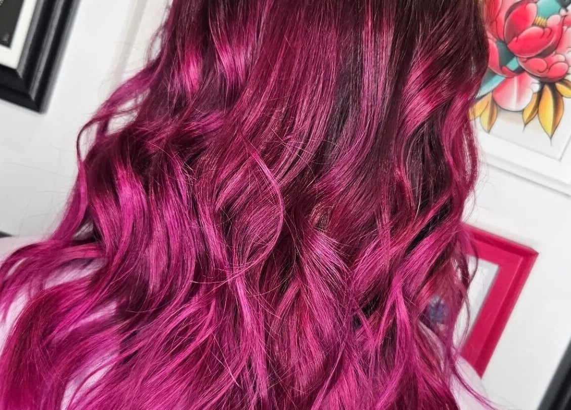 Rich magenta hair color at Crompton & Co, Heywood, England, GB, styled in elegant waves.