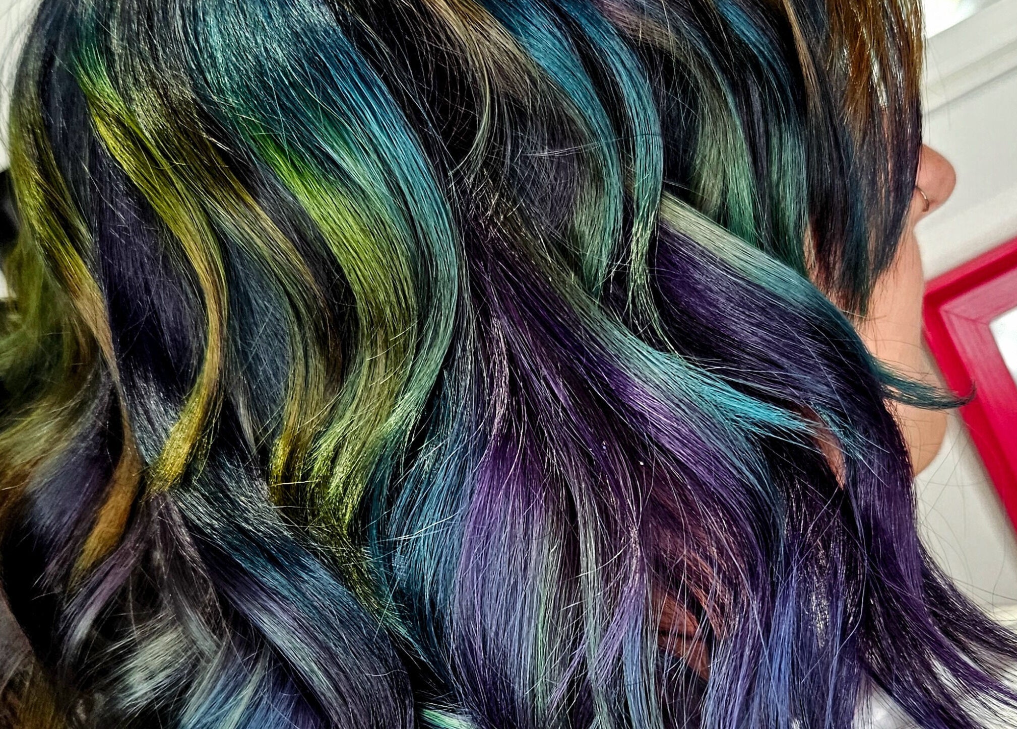 Vibrant rainbow-colored hair styled in waves at Crompton & Co, Heywood, England, GB.
