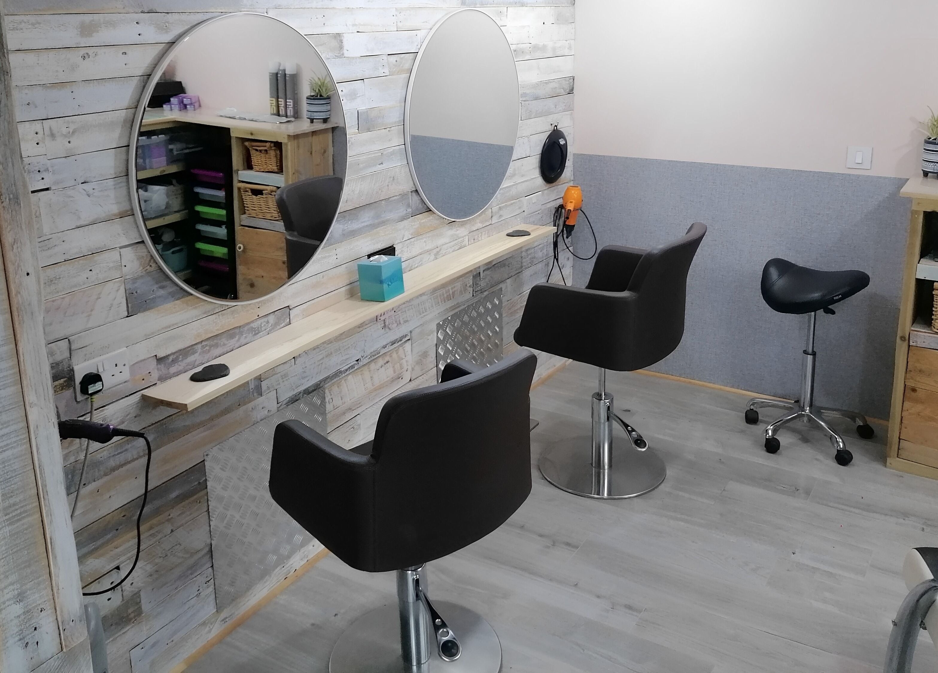 Elegant styling area with chic chairs at The Colourbox Hair Salon, Indian Queens, England, GB.