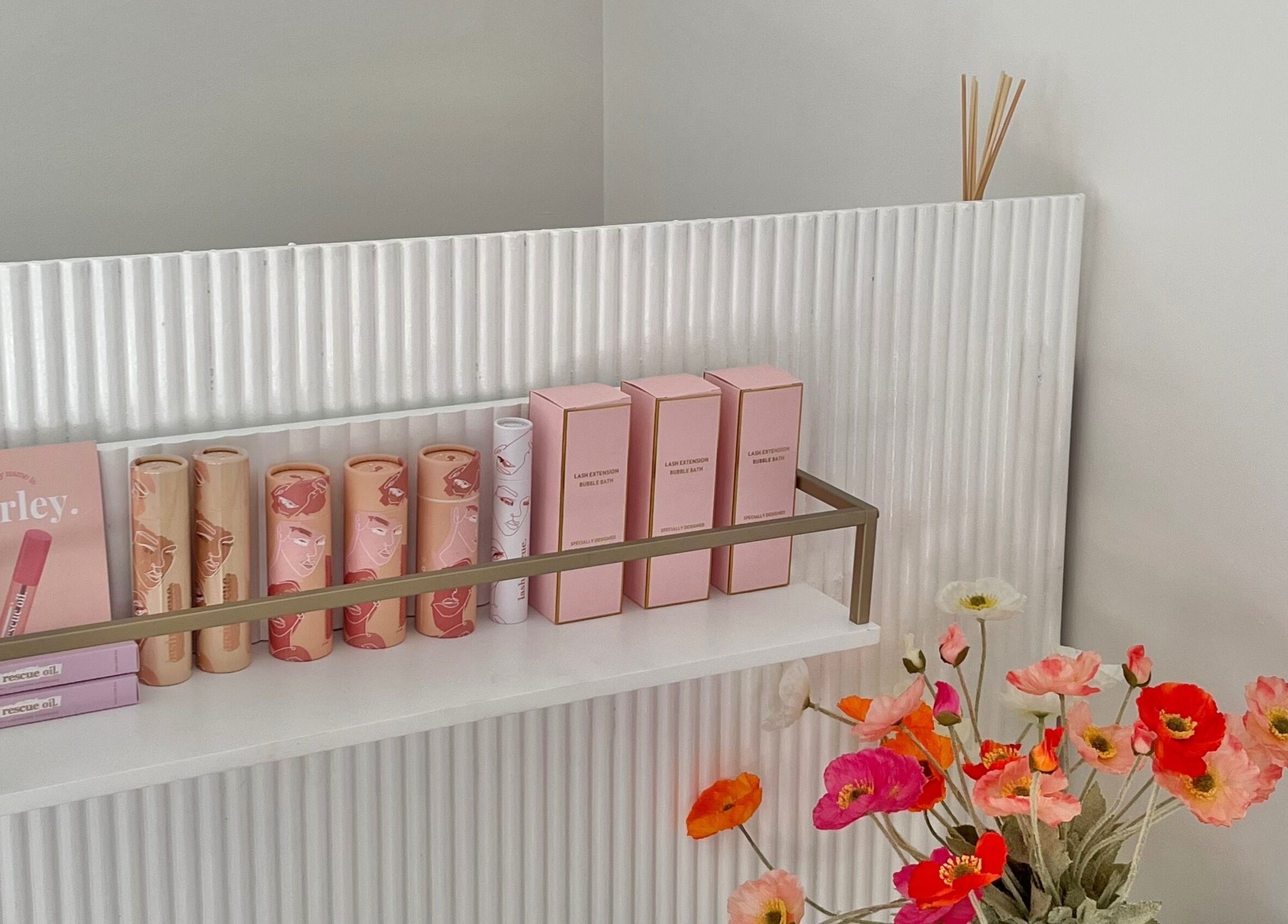 Elegant beauty products arranged on a shelf at Brow Stance in Bli Bli, Queensland, AU. Vibrant flowers add charm.