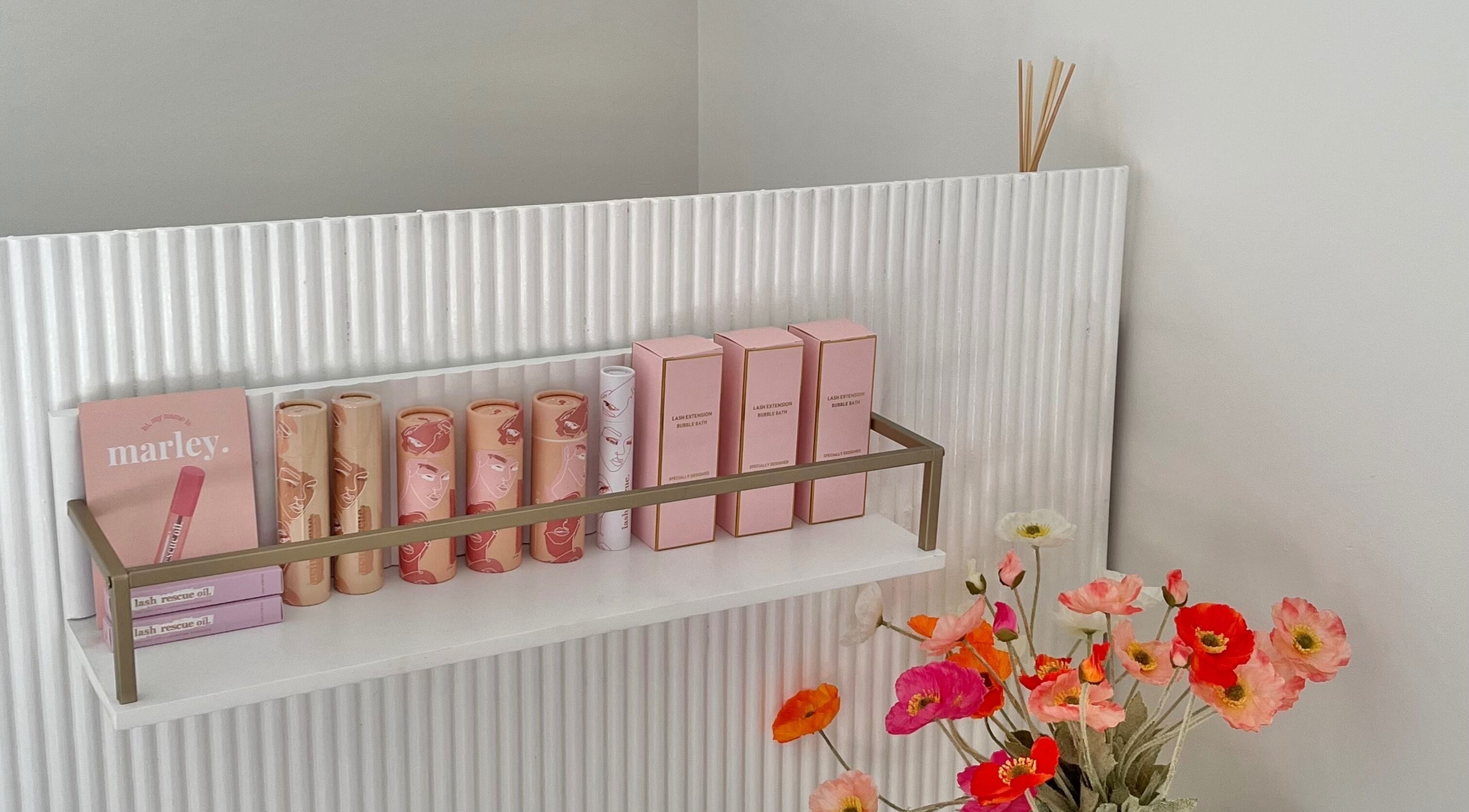 Elegant beauty products arranged on a shelf at Brow Stance in Bli Bli, Queensland, AU. Vibrant flowers add charm.