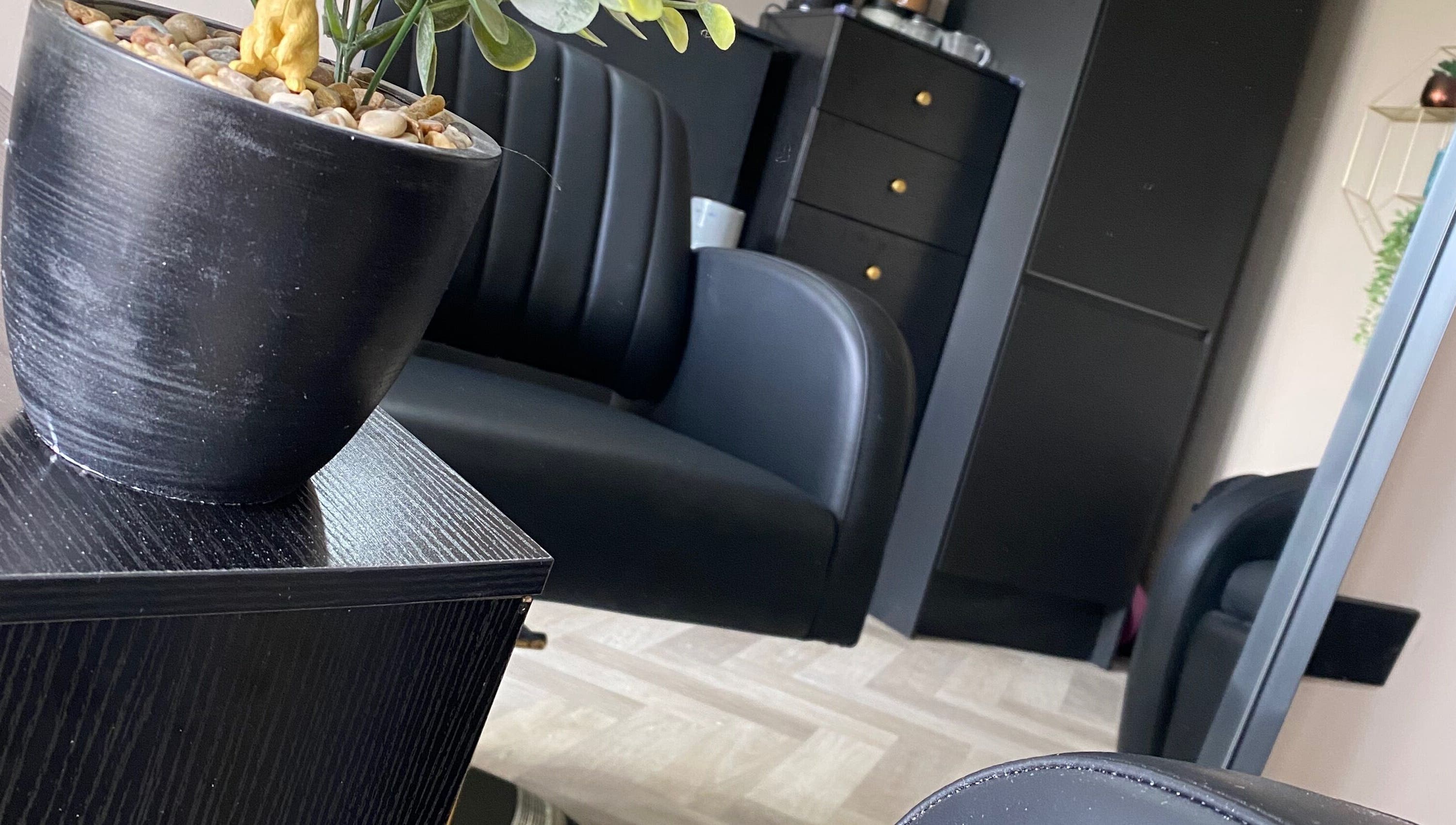 Elegant black seating at FabYouLocks salon in Motherwell, Scotland, GB. Modern, stylish interior with potted plant.