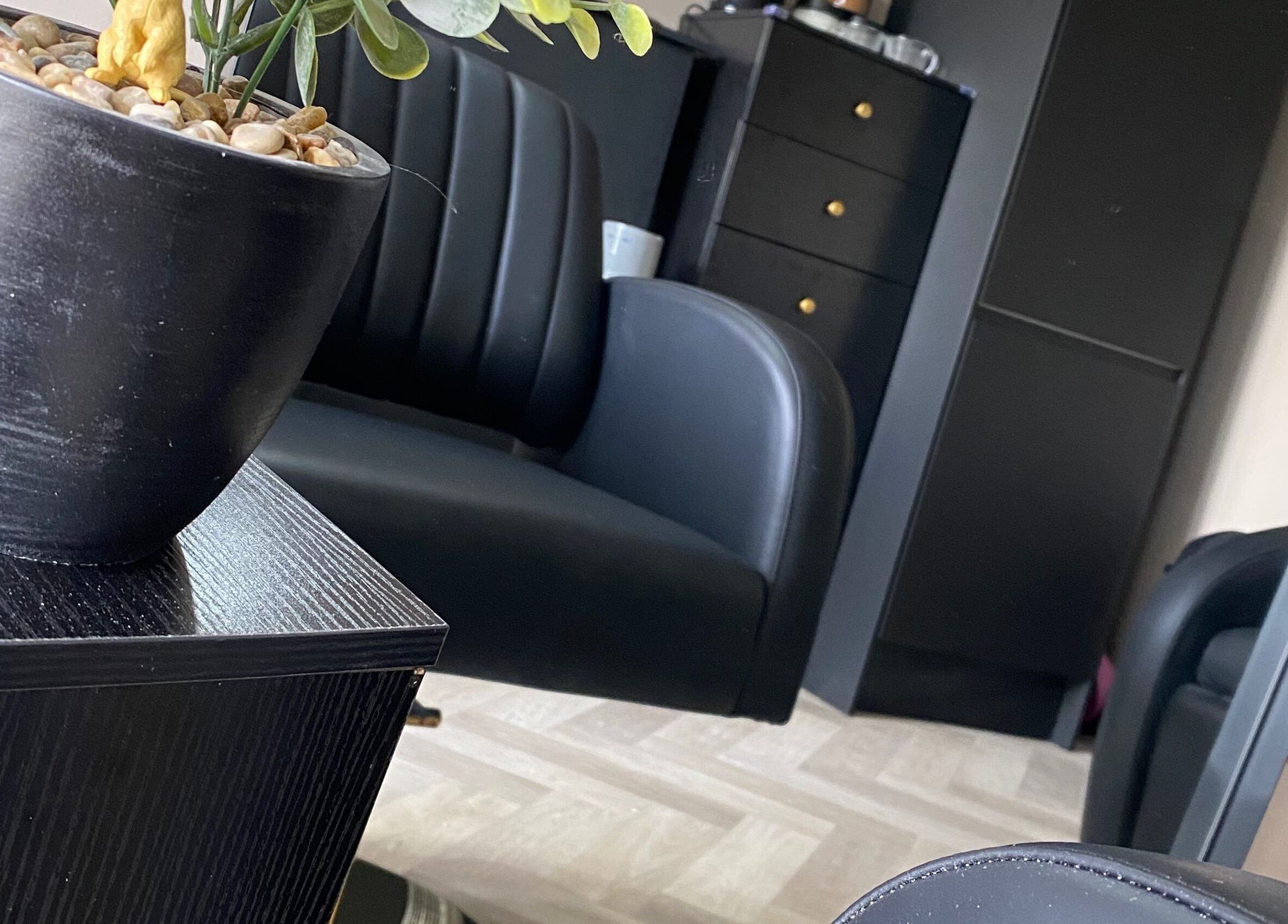 Elegant black seating at FabYouLocks salon in Motherwell, Scotland, GB. Modern, stylish interior with potted plant.