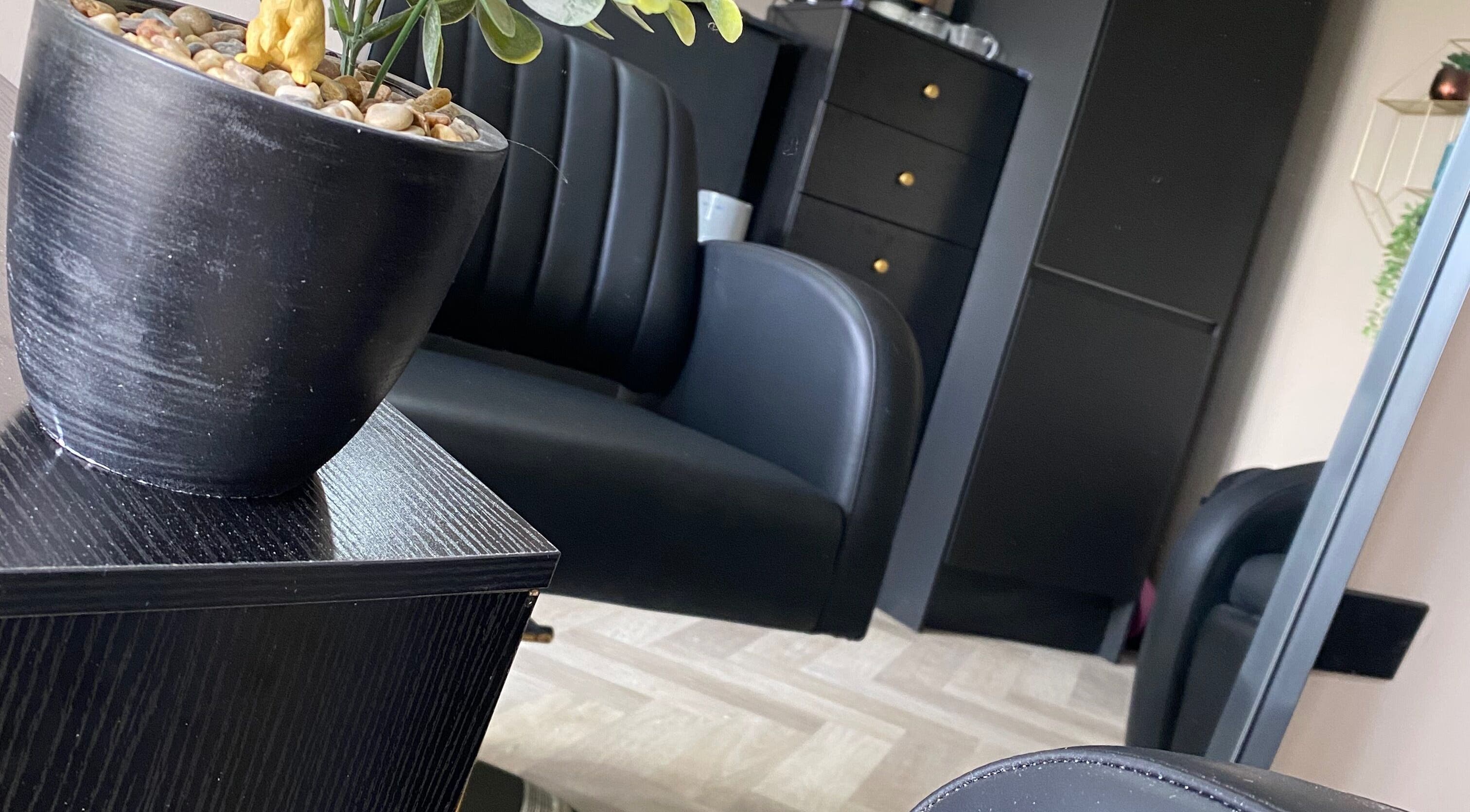 Elegant black seating at FabYouLocks salon in Motherwell, Scotland, GB. Modern, stylish interior with potted plant.