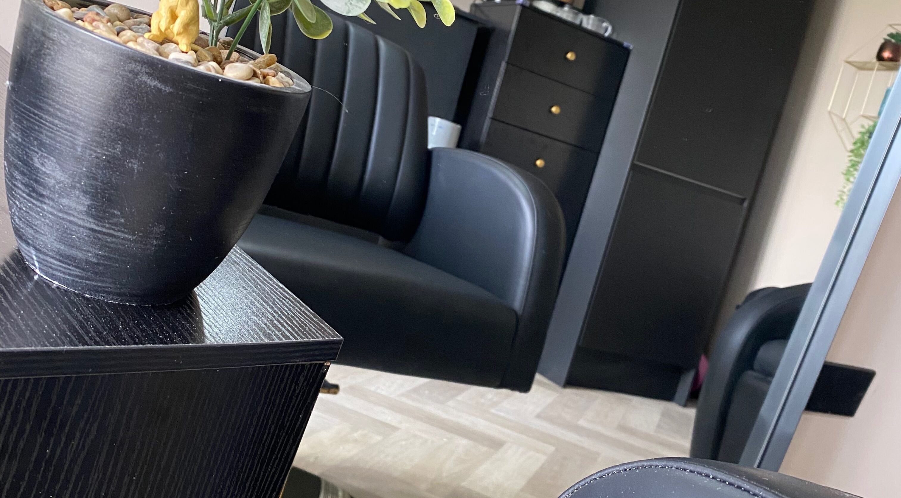 Elegant black seating at FabYouLocks salon in Motherwell, Scotland, GB. Modern, stylish interior with potted plant.