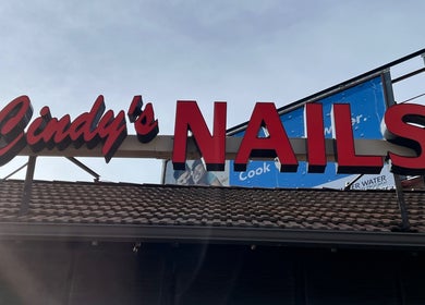 Bright red signage of Cindy's Nails on roof in Denver, Colorado, US, highlights beauty service location.