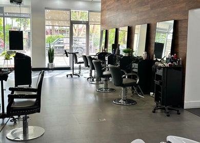 Modern salon interior at NEW by CARO RIBEIRO in South Miami, Florida, US with sleek styling chairs and large mirrors.