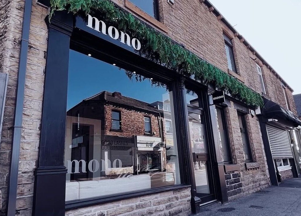 Mono's stylish stone facade in Hoyland, England, GB, reflecting neighboring shops under a clear sky.