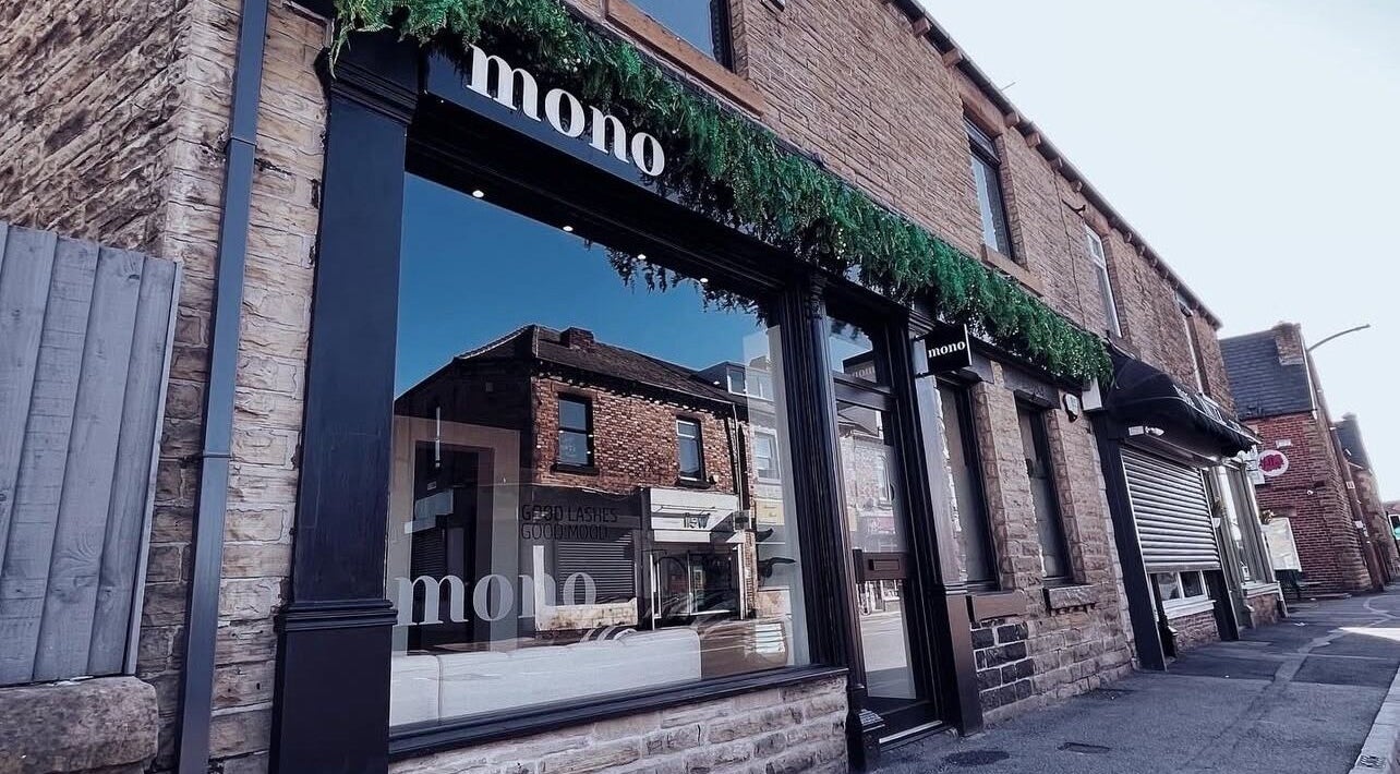 Mono's stylish stone facade in Hoyland, England, GB, reflecting neighboring shops under a clear sky.