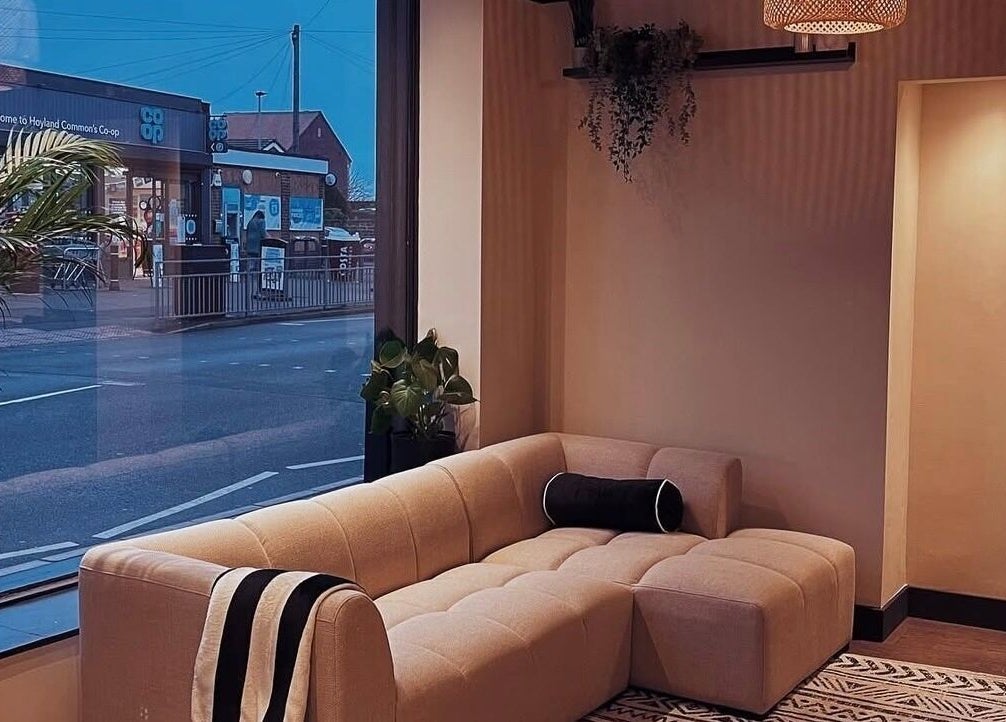 Cozy lounge area at Mono, Hoyland, England, GB with modern sofa, window view, and greenery.