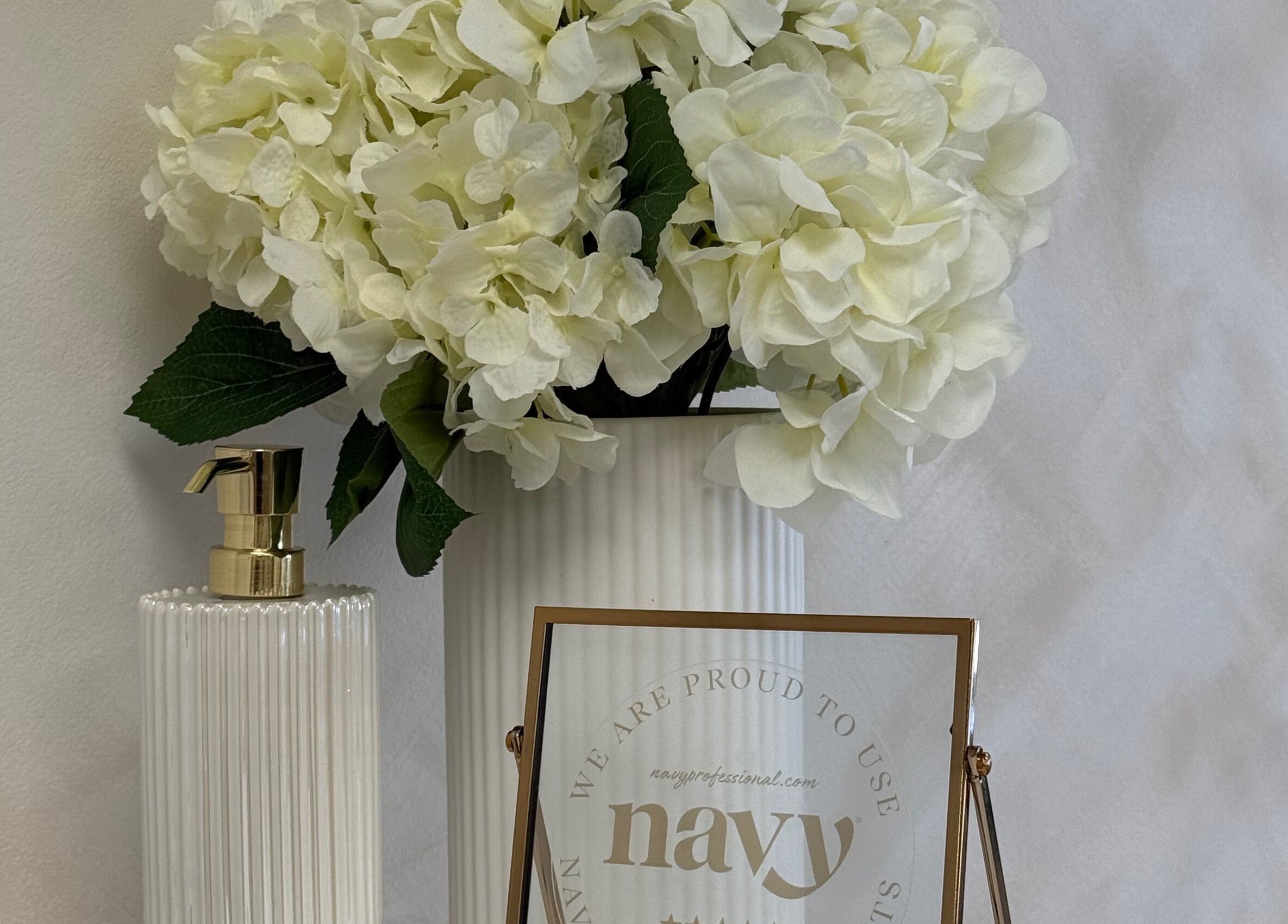 Elegant decor at Olive Nails Studio, Kilmarnock, Scotland with white flowers and a stylish soap dispenser.