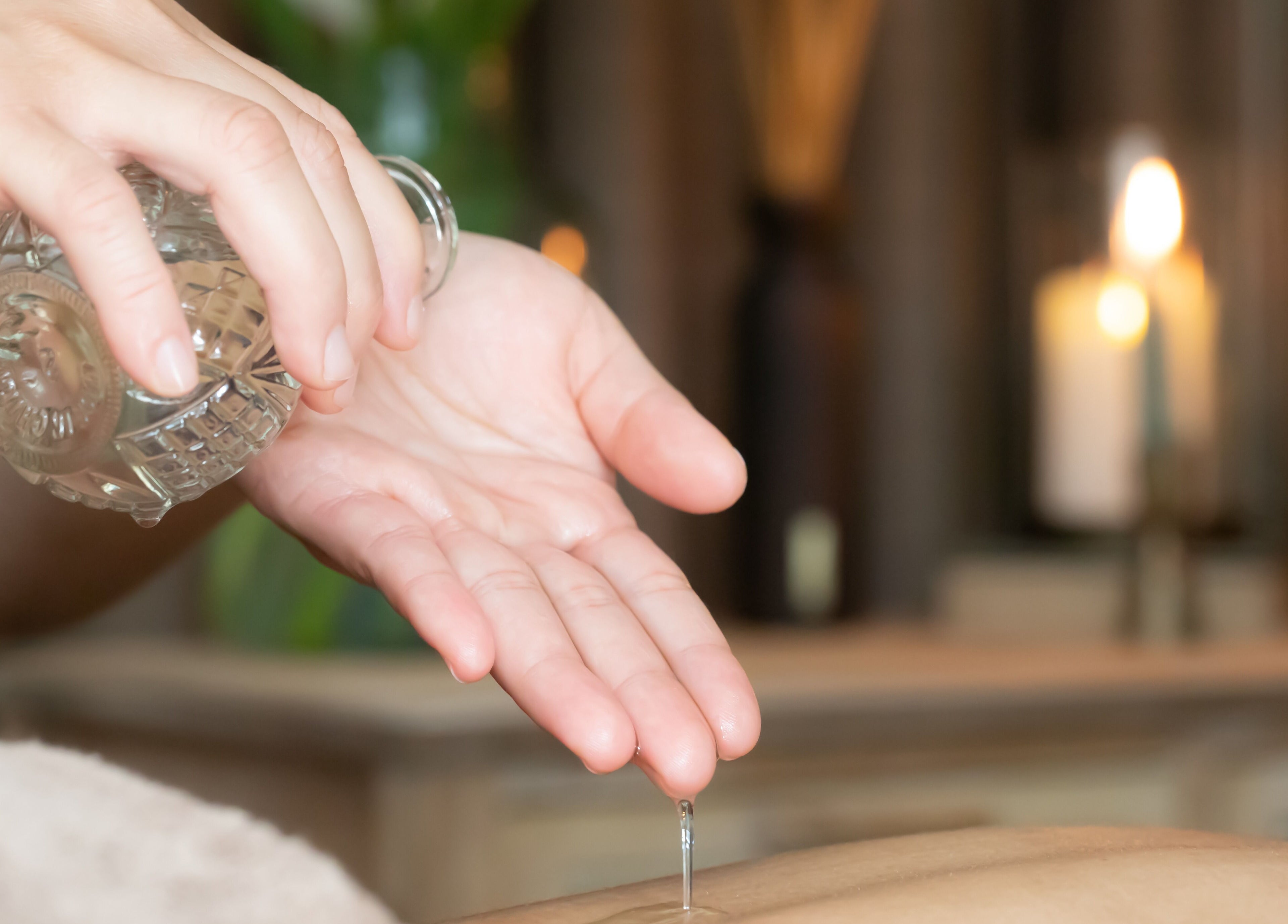 Massage oil being poured at Chada Wellness, Sassenheim, Zuid-Holland, NL with soothing candlelight.