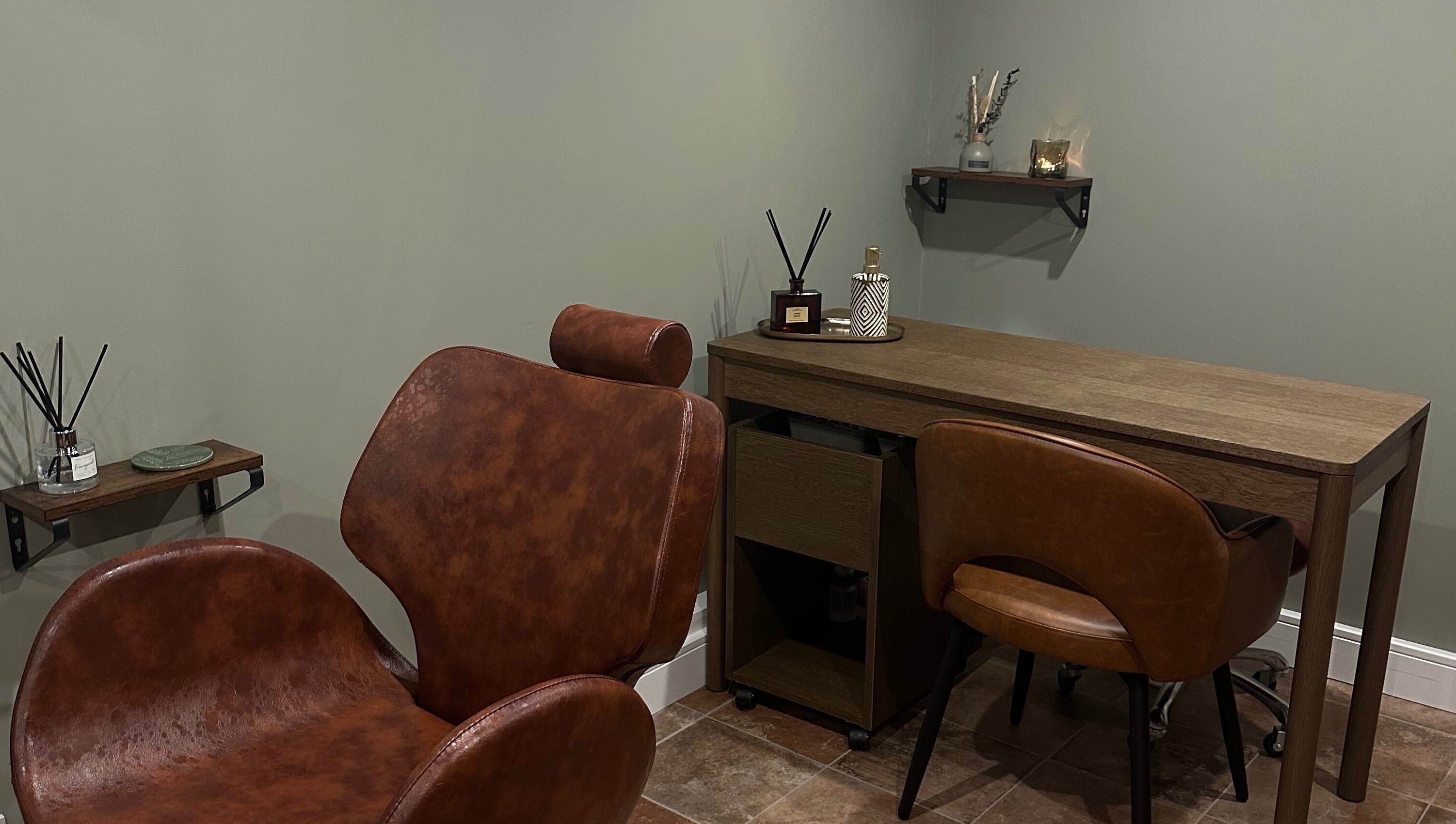 AJ Beauty Studio cozy treatment area with brown chairs and wooden desk in Hucknall, England, GB.