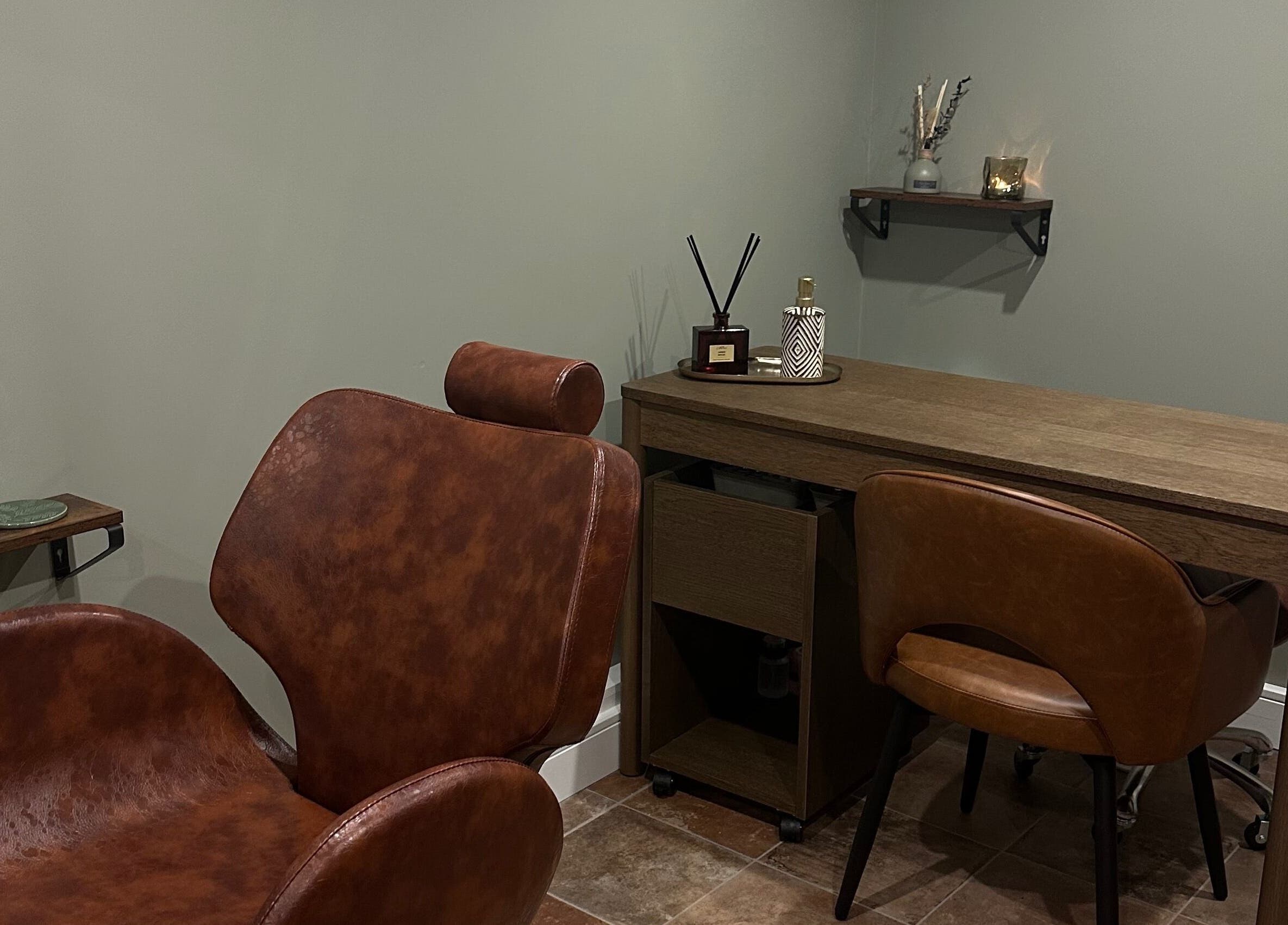 AJ Beauty Studio cozy treatment area with brown chairs and wooden desk in Hucknall, England, GB.