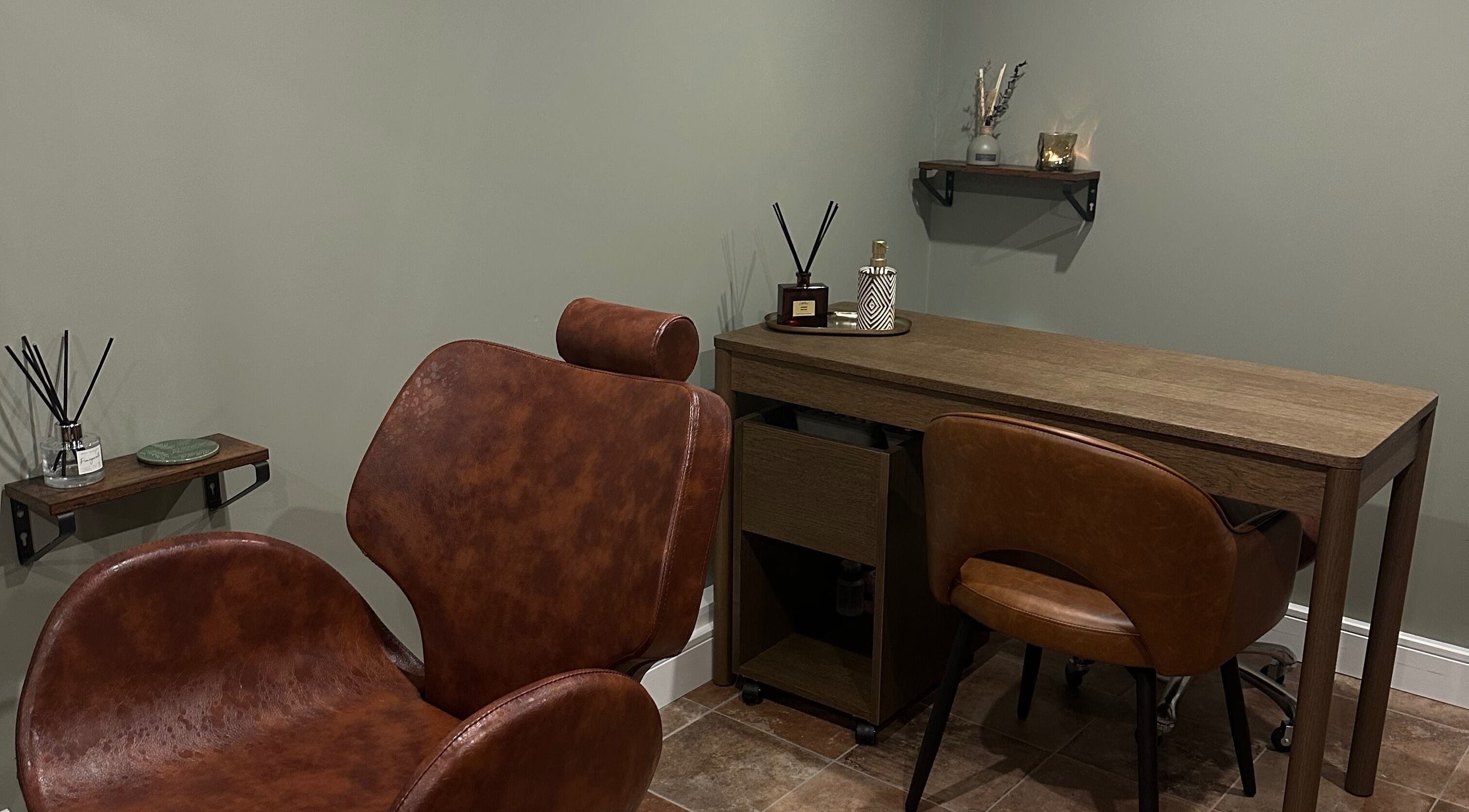 AJ Beauty Studio cozy treatment area with brown chairs and wooden desk in Hucknall, England, GB.