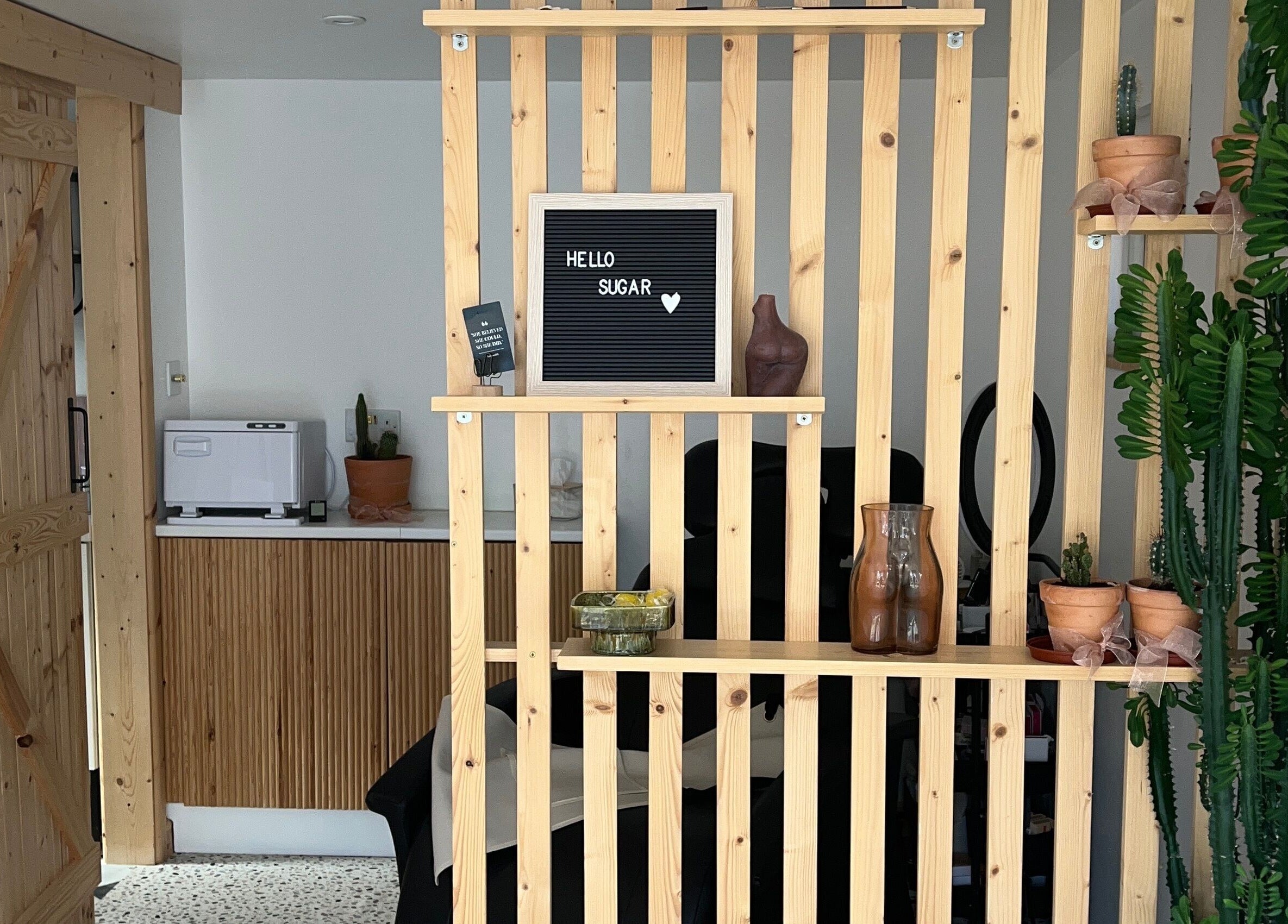 Chic wooden decor at Sugared by Shola in Bristol, England, GB, featuring cacti and modern furnishings.