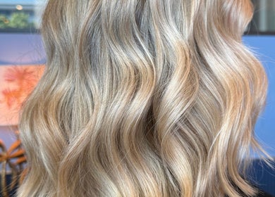 Blonde wavy hair styled at Maddi Jane Hair Studio, Southport, Queensland, AU with a vibrant salon backdrop.
