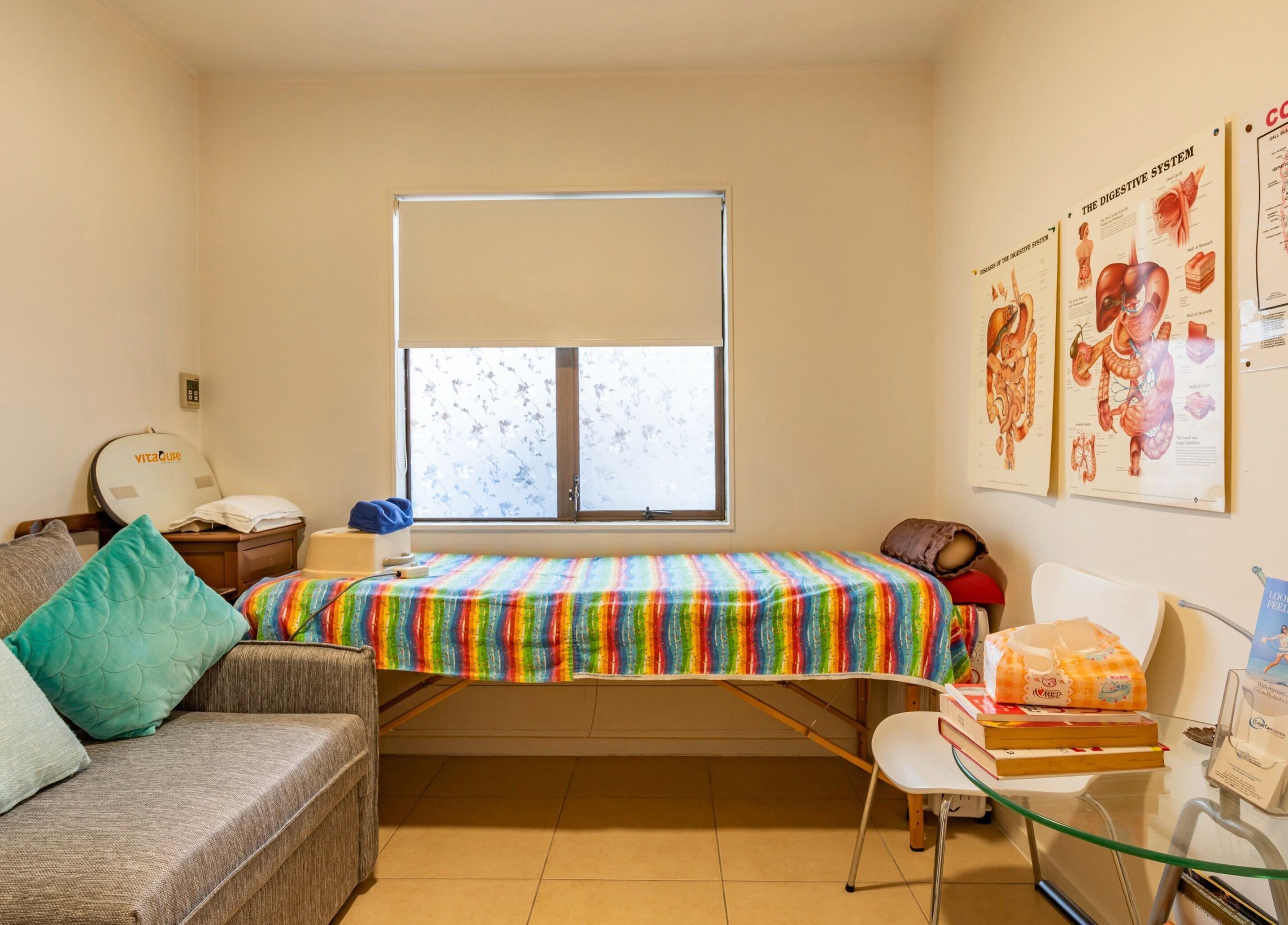 Therapy room at Colon Care Centre in Auckland, NZ, featuring a treatment bed and educational posters.