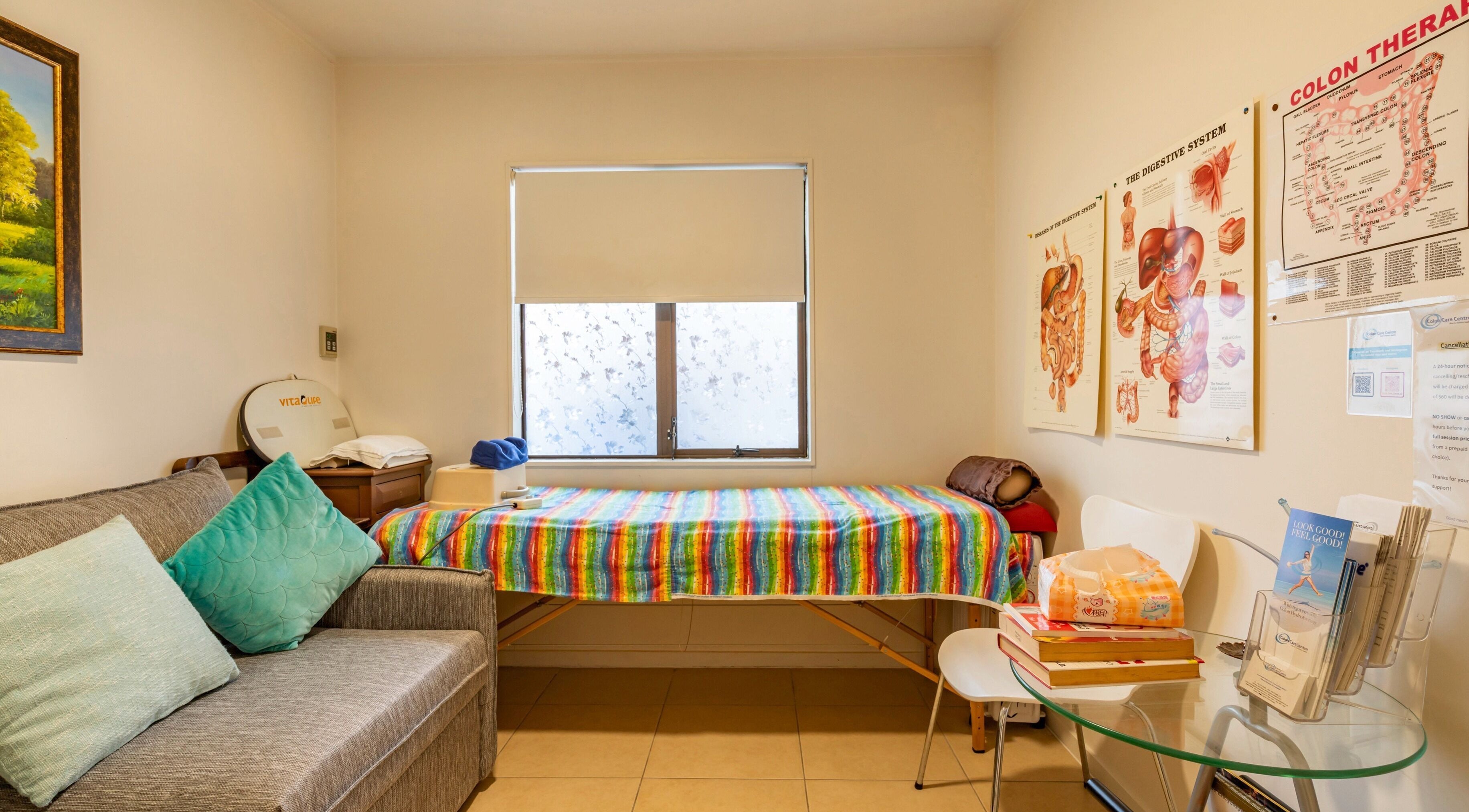 Therapy room at Colon Care Centre in Auckland, NZ, featuring a treatment bed and educational posters.