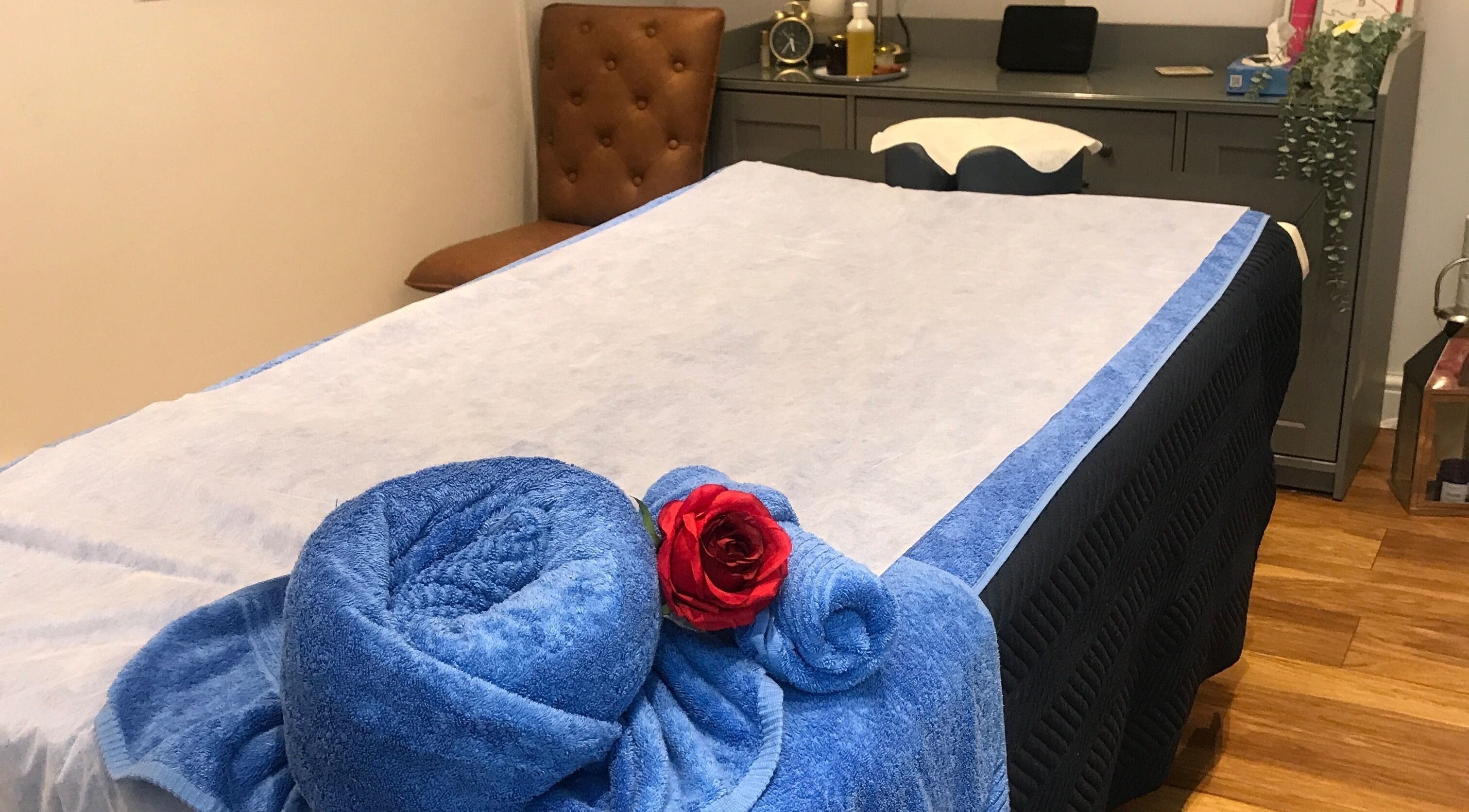Cozy massage room at Thawee Thai Therapy, Solihull, England. Blue towels and red rose on treatment table.