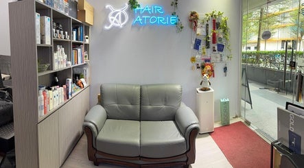 Reception area at Hair Atorie in Singapore, SG with a grey sofa, product display, and a welcoming atmosphere.
