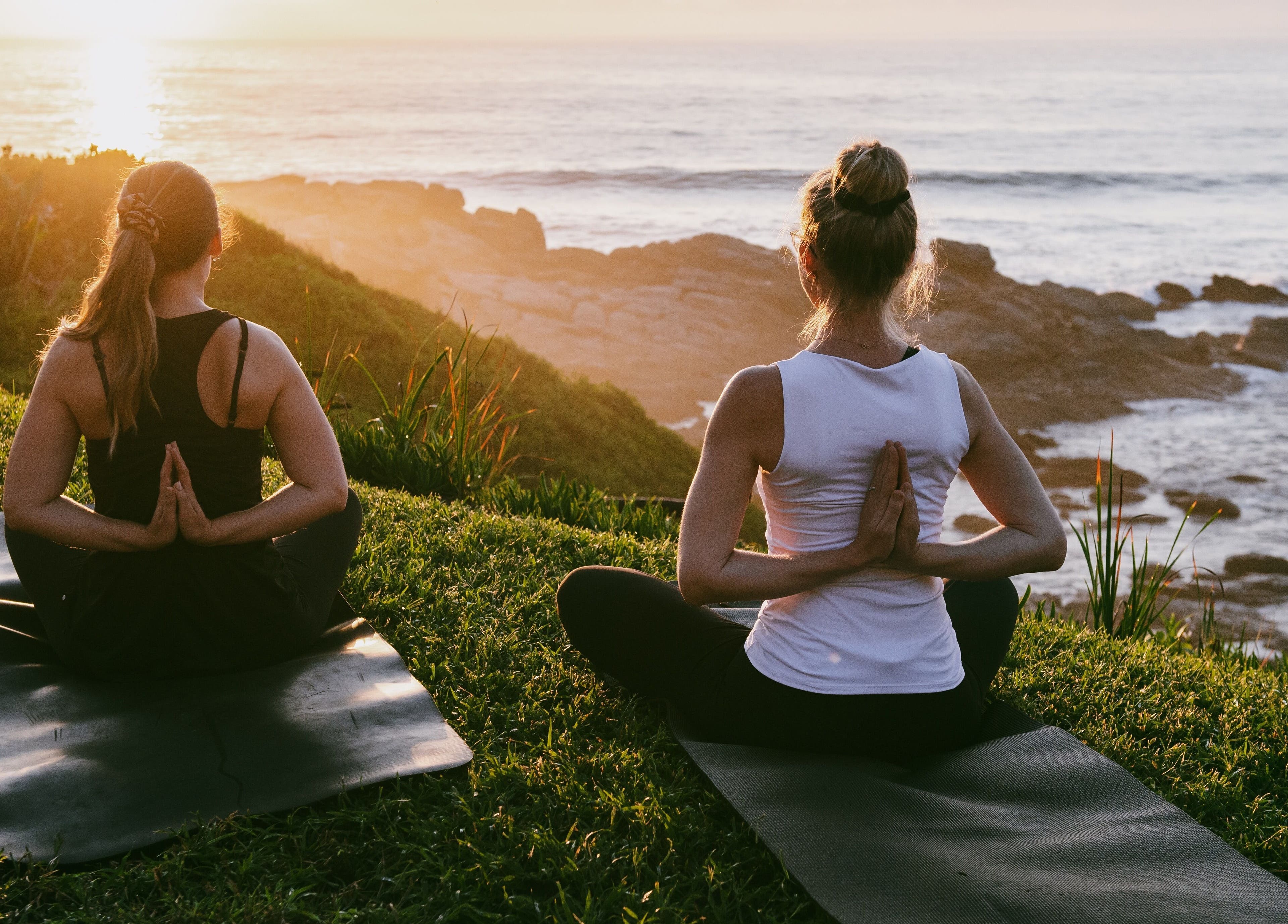 Two people meditating at Sala Beach Spa, Dolphin Coast, KwaZulu-Natal, ZA during a stunning ocean sunset.