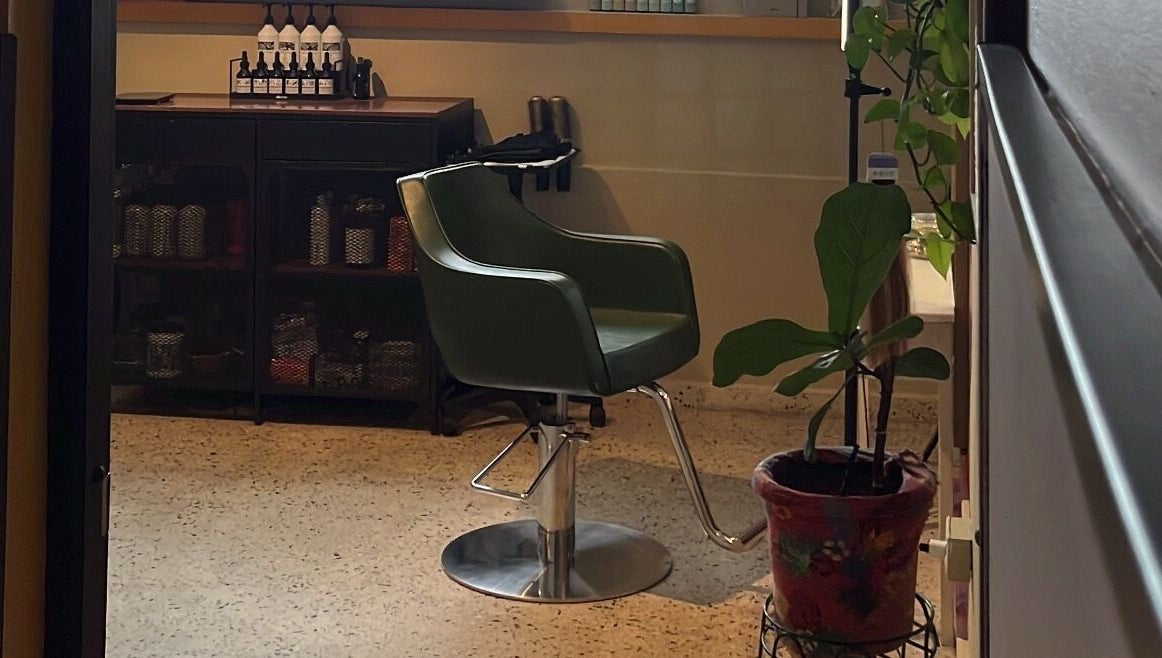 Silla estilista en Dejame Hacer tu Cabello, Arecibo, Arecibo, PR, junto a productos y planta decorativa.