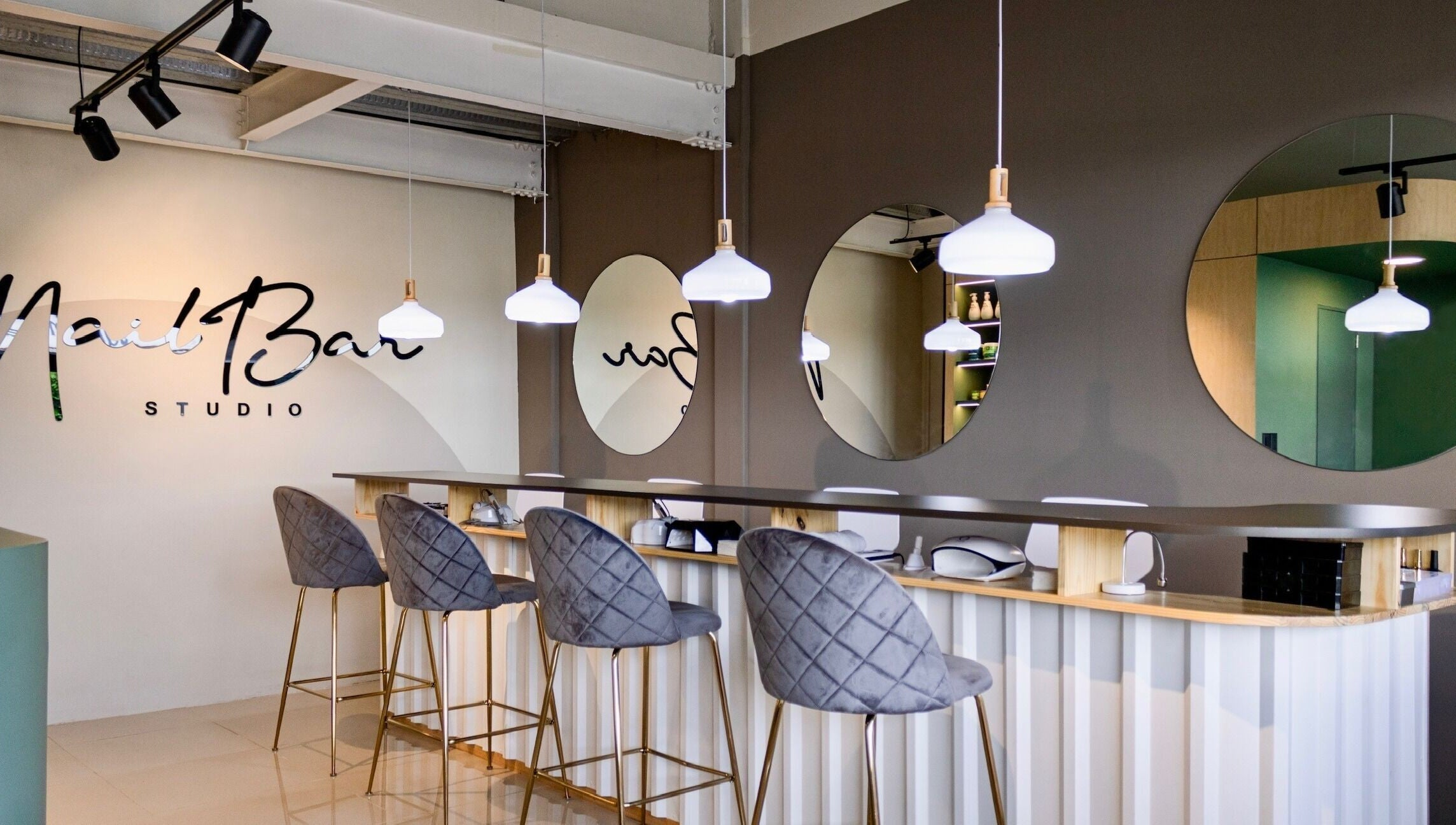 Interior moderno de Nail Bar Plaza Pinula en Guatemala, Guatemala, GT con sillas grises y espejos circulares.