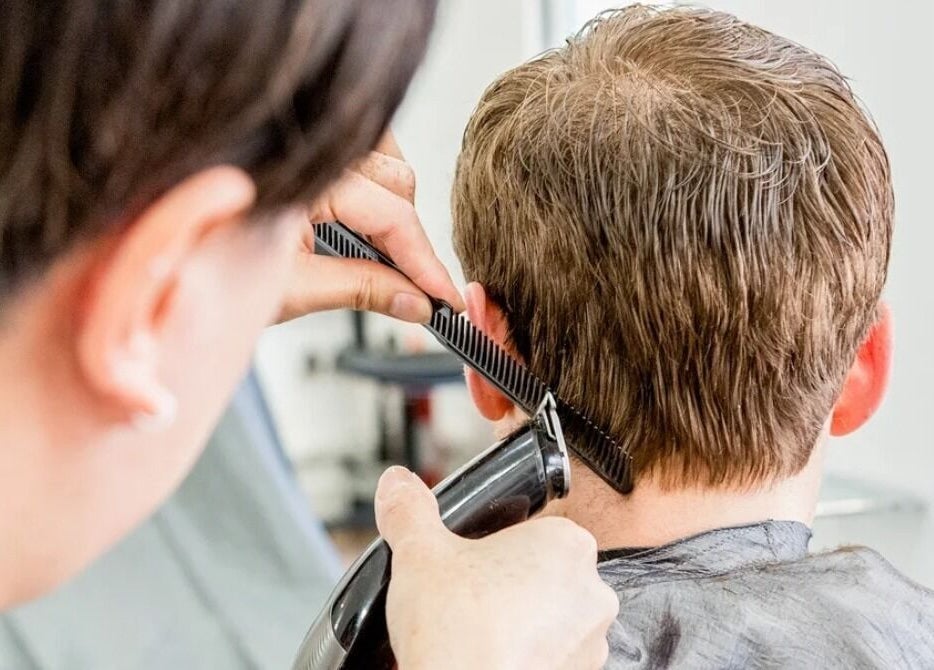 Haircut in progress at The Cut Studio (Hair) in London, England, GB. A stylist uses clippers and comb.