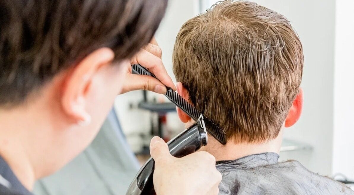 Haircut in progress at The Cut Studio (Hair) in London, England, GB. A stylist uses clippers and comb.