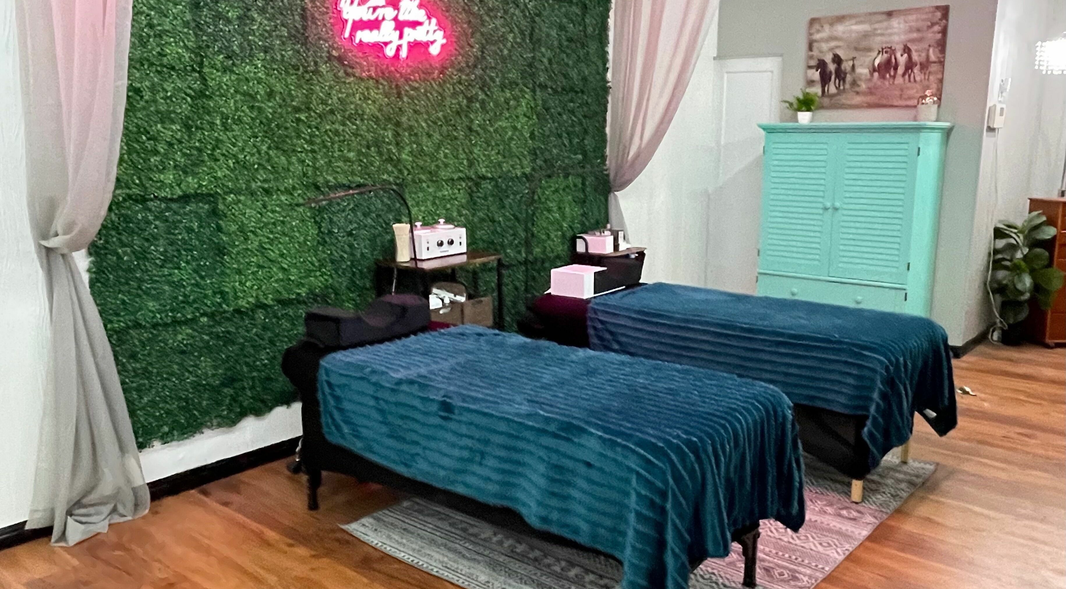 Relaxing therapy room at Spur Salon in Duchesne, Utah, US with two massage tables and lush greenery wall.