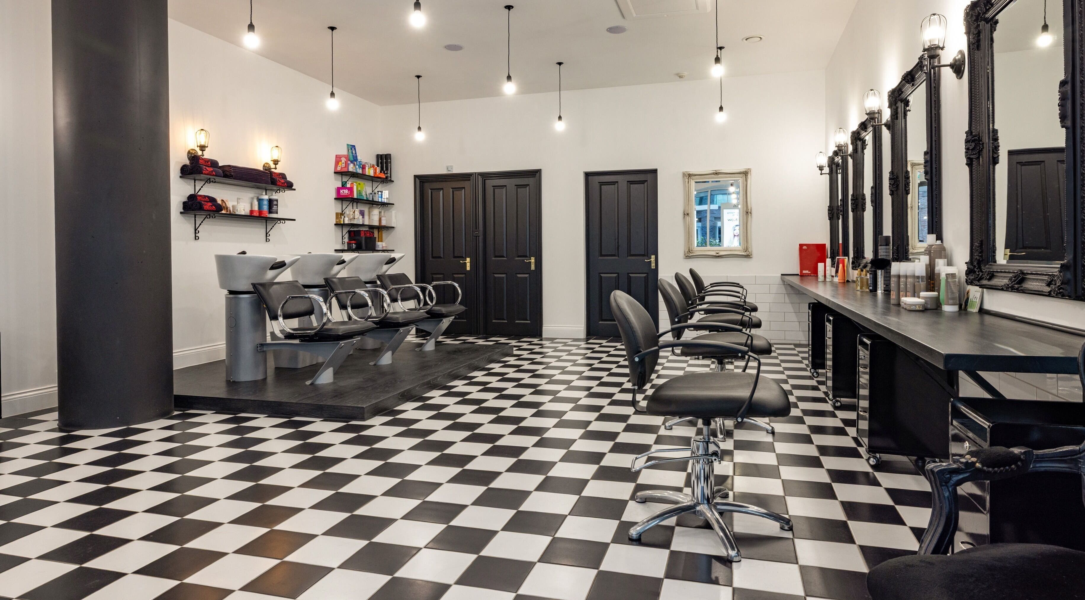 Modern interior of Vida hair & beauty Aldgate, London, England, GB featuring stylish chairs and mirrors.