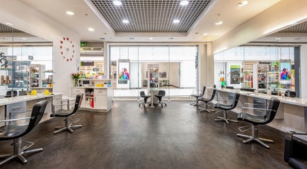 Modern, stylish salon interior at Vida Hair & Beauty The Mercury, Romford, England, GB with sleek black chairs.