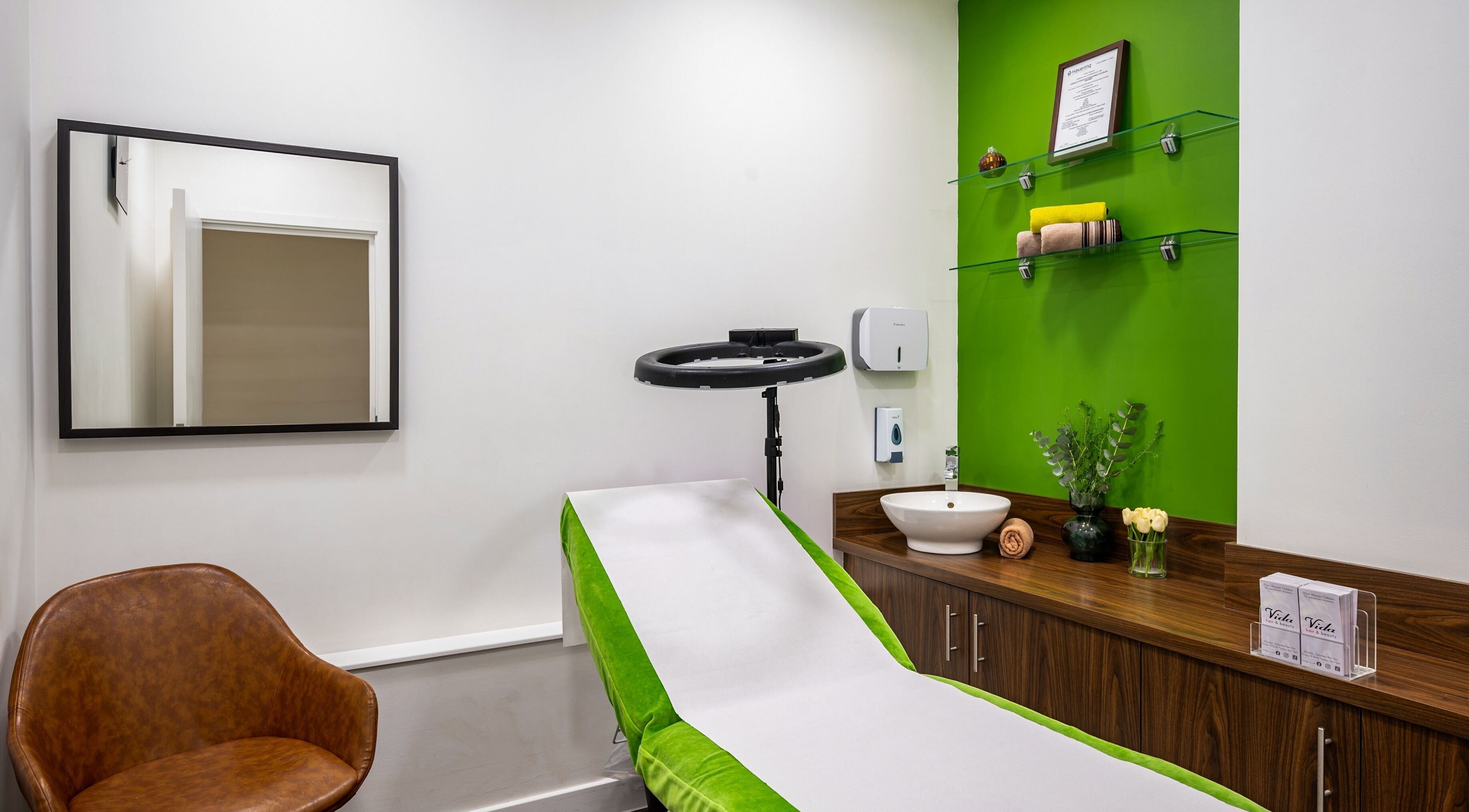 Private treatment room at Vida Hair & Beauty The Mercury, Romford, England, featuring modern decor and green accents.