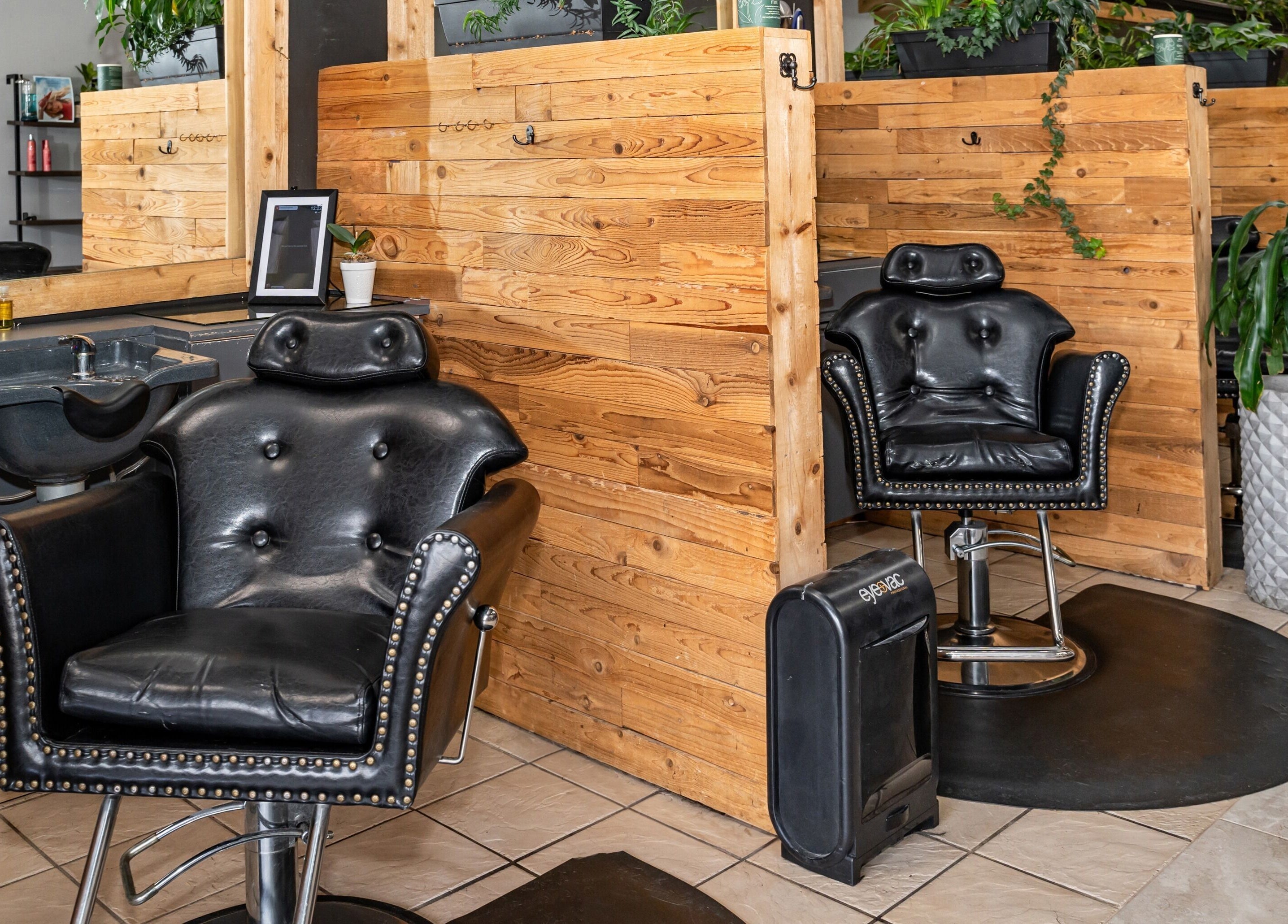 Modern styling station at Obsessed Salon in Aurora, Colorado, US, featuring sleek black chairs and wooden decor.