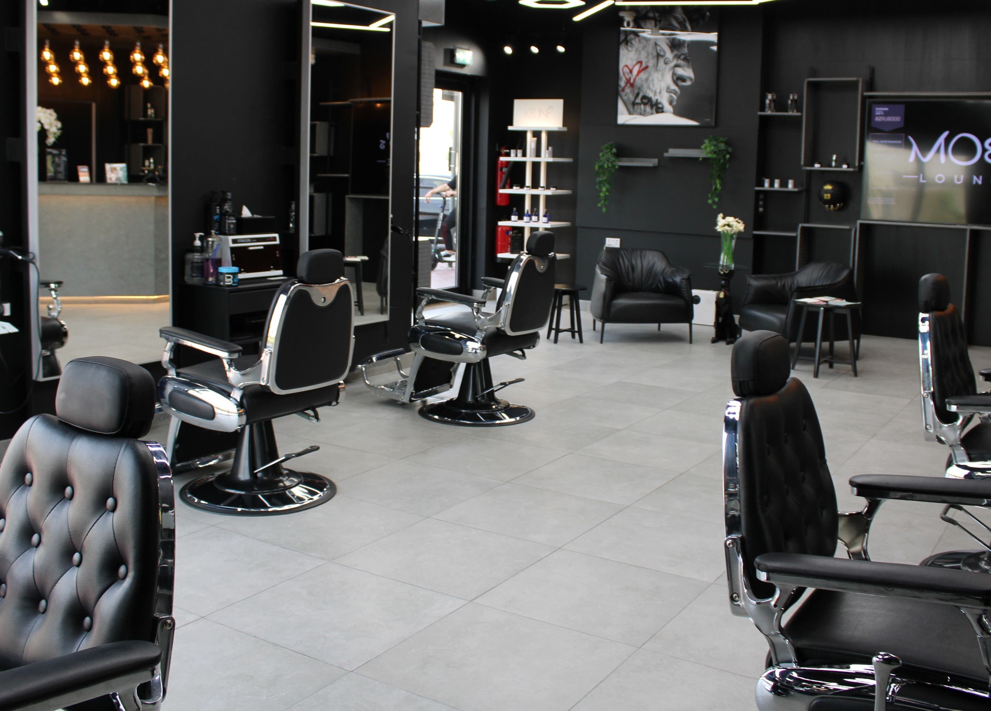 Modern interior of Moe's Lounge - Jumeirah Garden City, featuring sleek barber chairs. Dubai, AE.