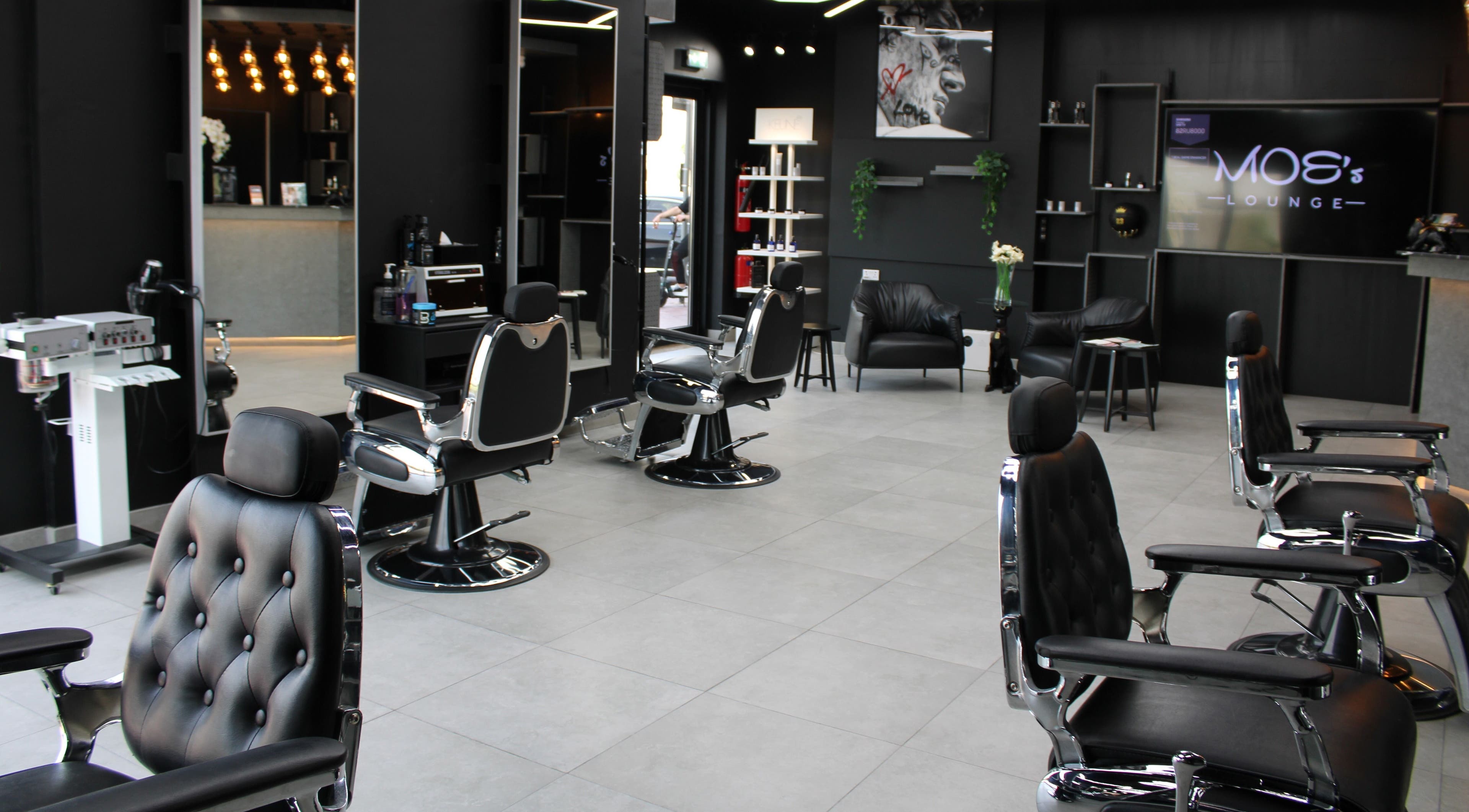Modern interior of Moe's Lounge - Jumeirah Garden City, featuring sleek barber chairs. Dubai, AE.
