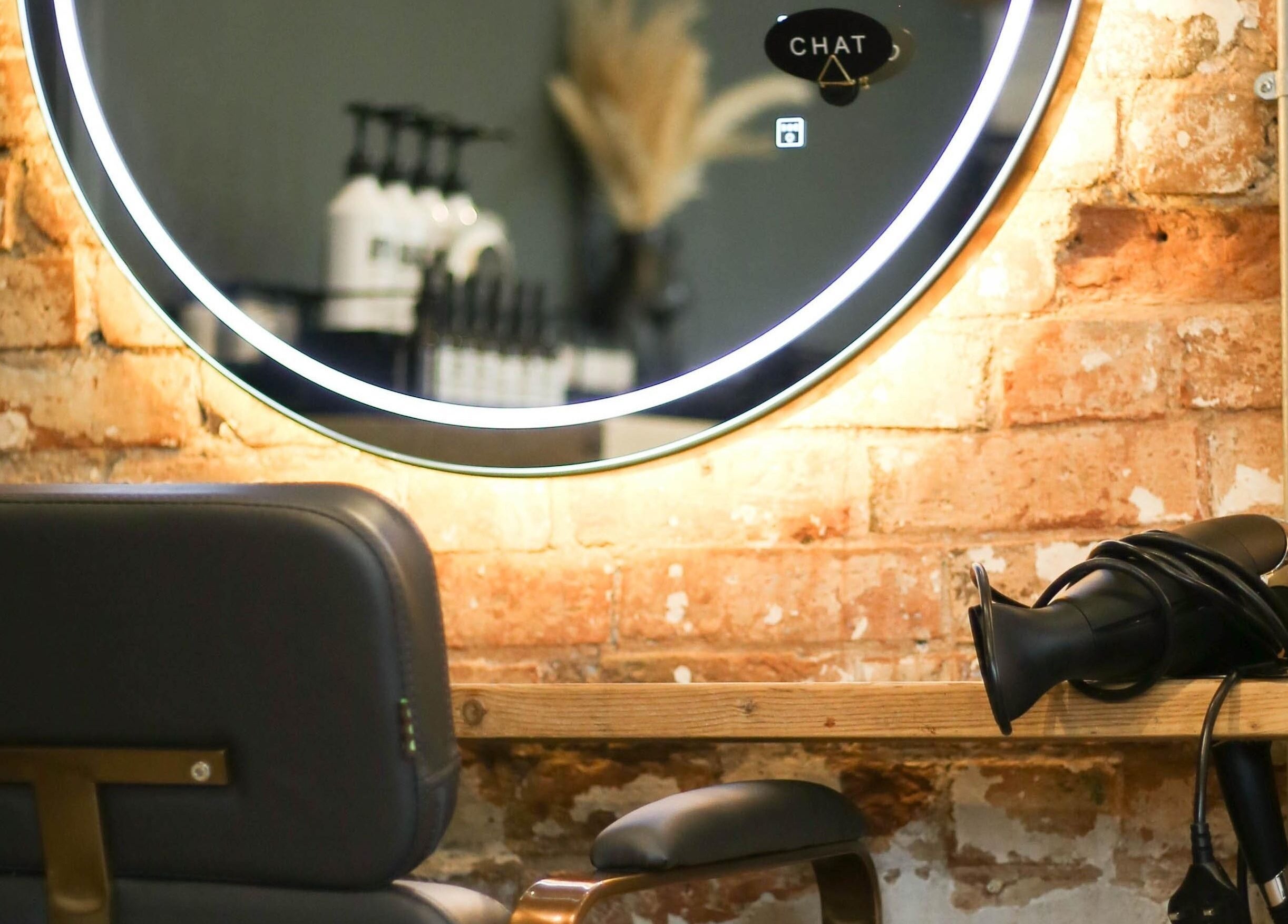 Modern salon chair and mirror at Mane, Huncote, England, GB with exposed brick wall.