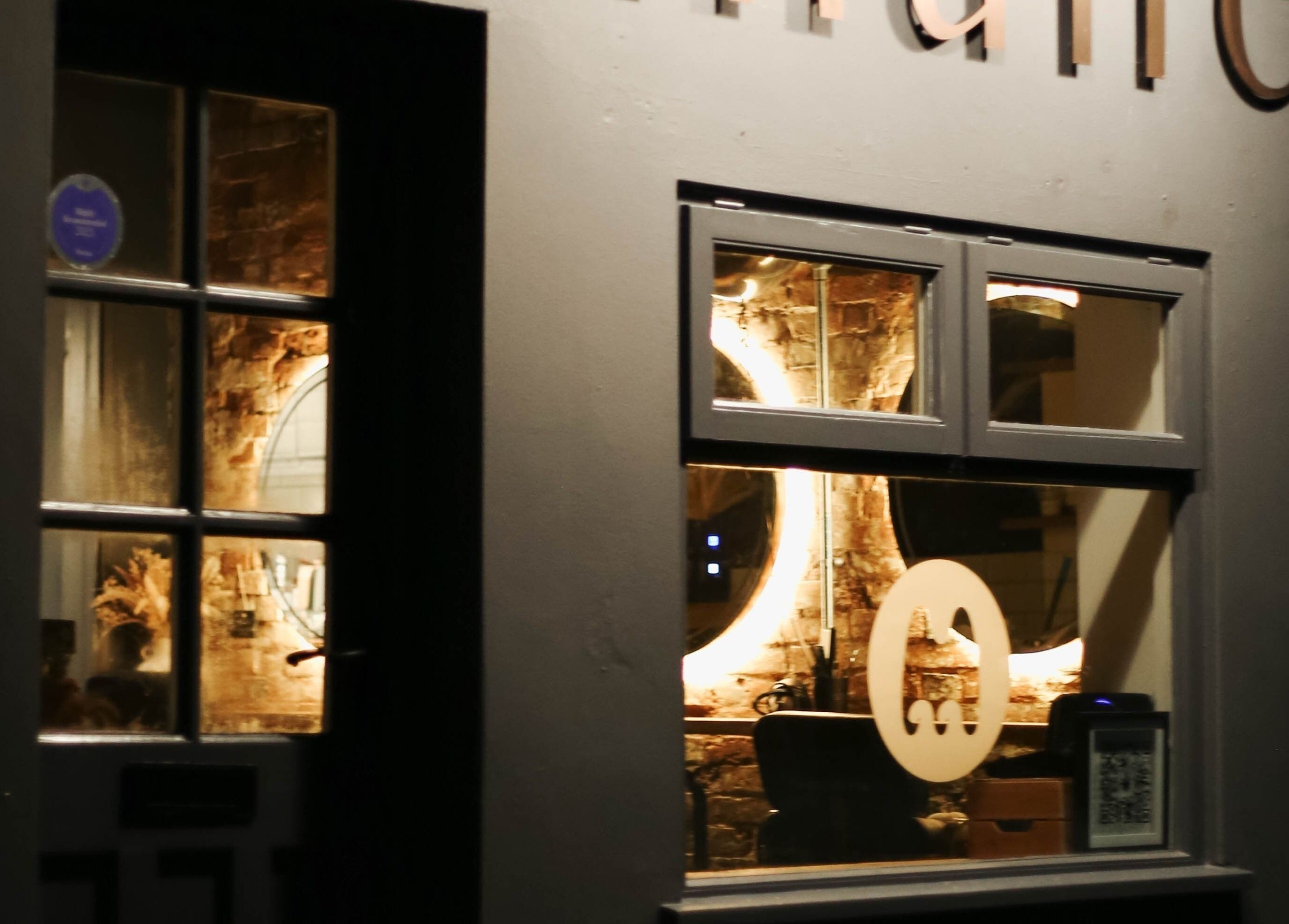 Warm, inviting entrance of Mane salon in Huncote, England, GB illuminated at night.