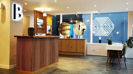 Reception area at Maritza Aesthetics, Portsmouth, England with modern wooden decor and round mirrors.