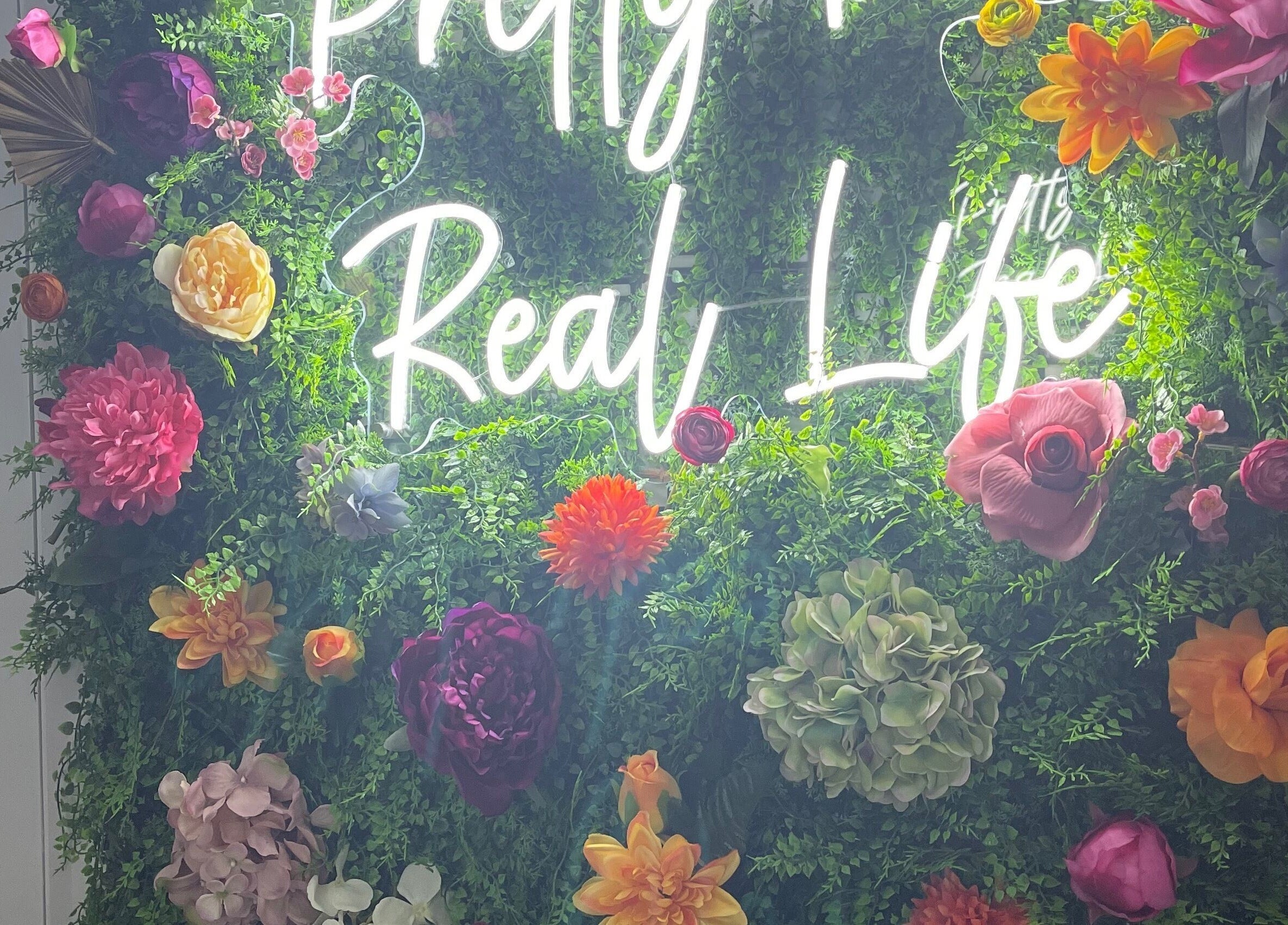 Vibrant floral wall with neon sign at Beautè Dolls, Luton, England, GB.