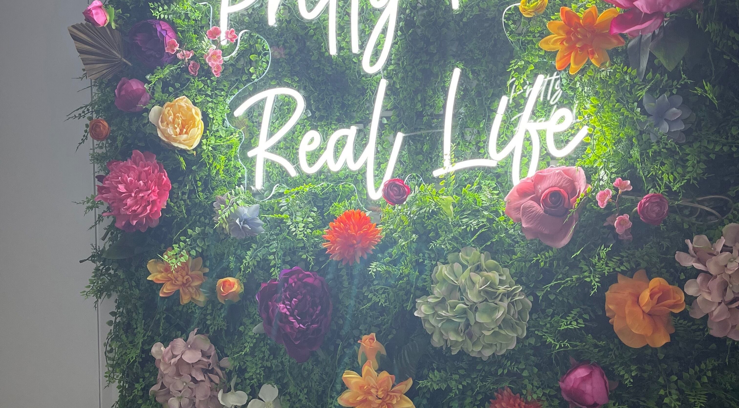 Vibrant floral wall with neon sign at Beautè Dolls, Luton, England, GB.