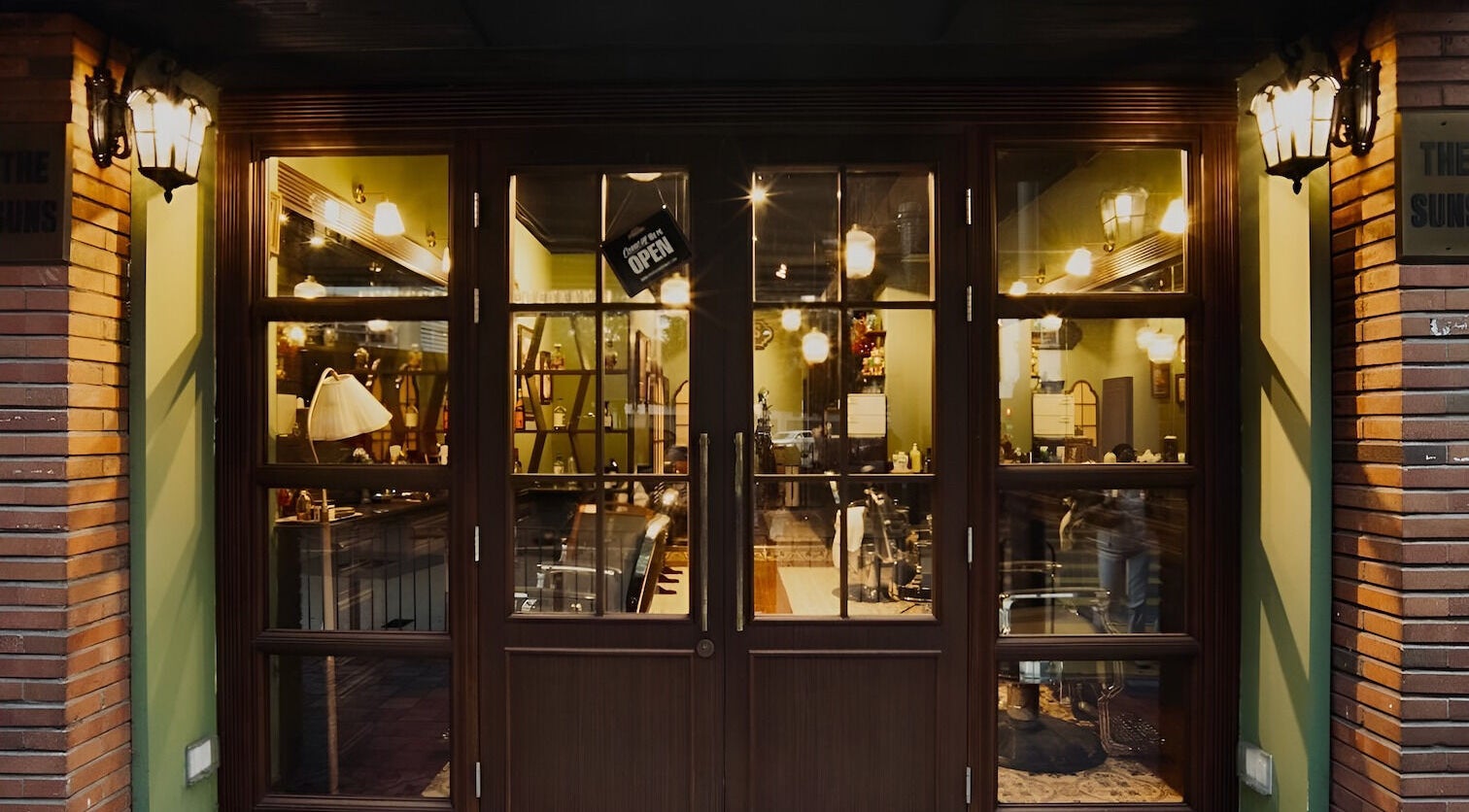 Warmly lit entrance of The Suns Barbershop in 香港島, 香港島, HK, highlighting a classic and inviting ambiance.