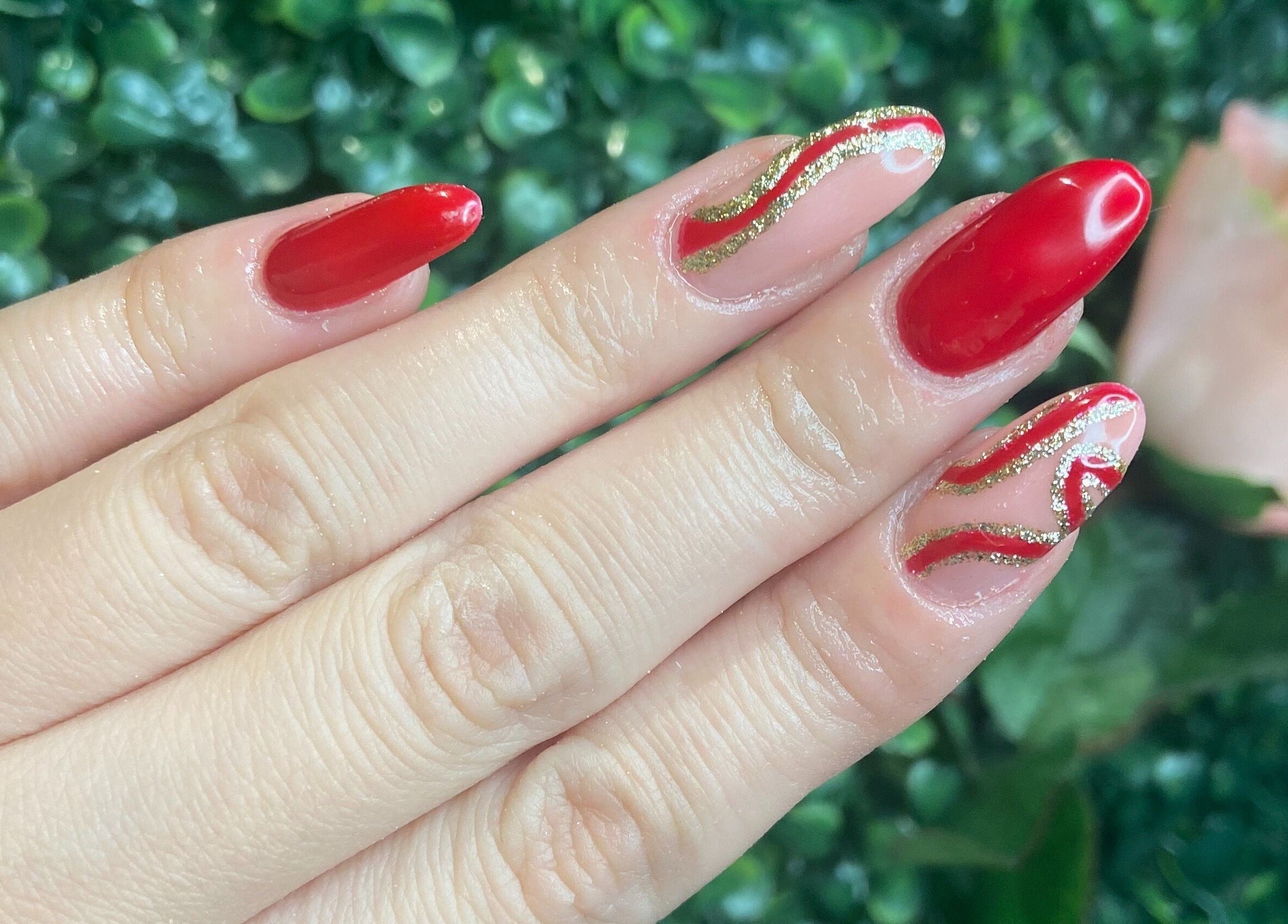 Stylish red nails with gold accents at KatieBea Beauty in Dundee, Scotland, GB.