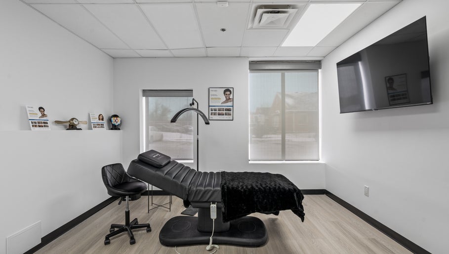 Modern treatment room at Beauty Matched Med Spa, Sarnia, Ontario, CA featuring a sleek black chair and large TV.